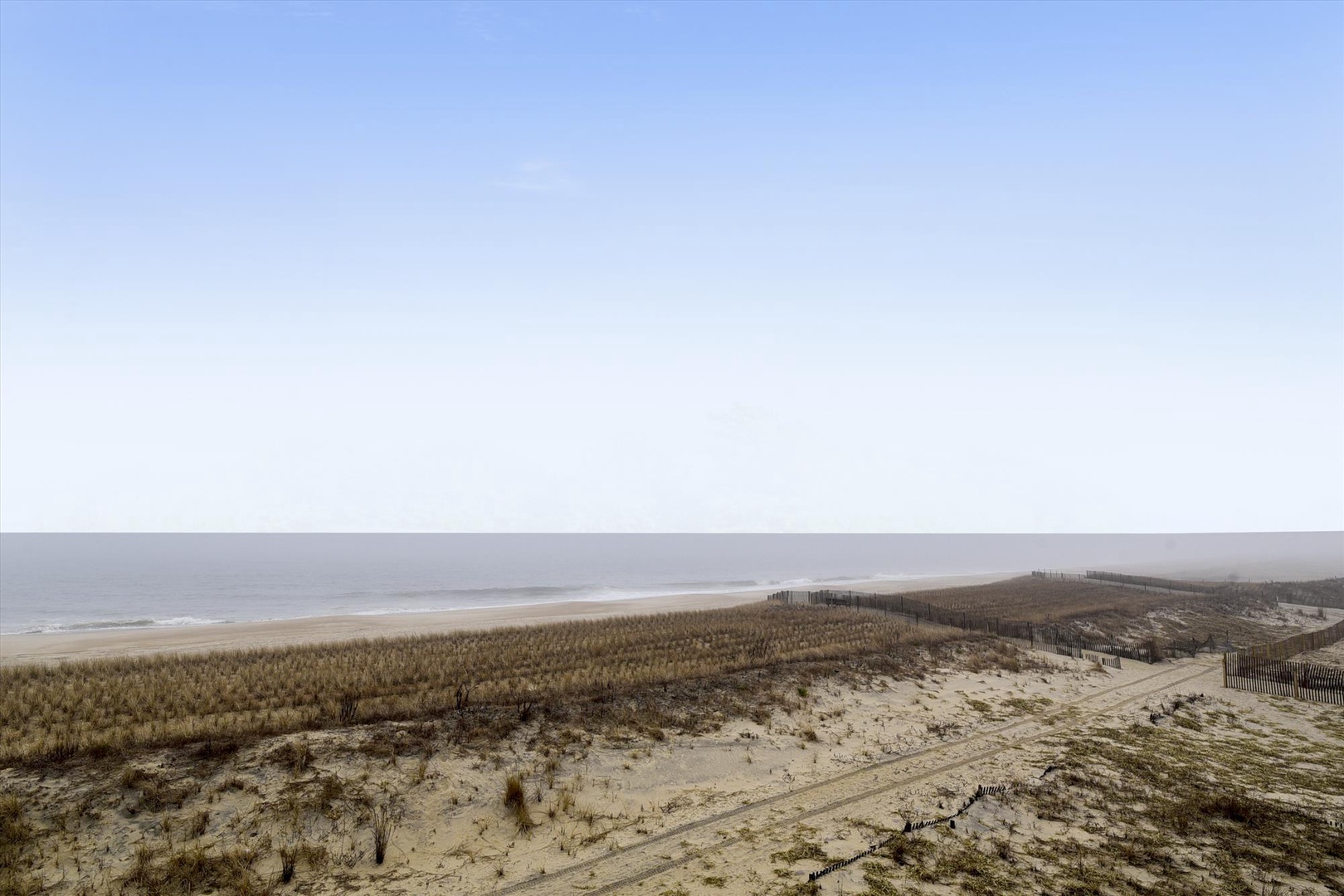 Expansive coastal landscape featuring pristine sandy beaches and natural dune vegetation stretching toward the horizon.