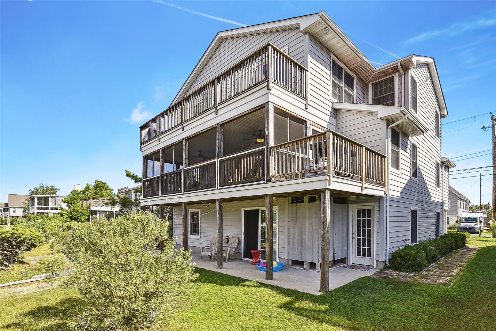 This spacious coastal home features multiple balconies and a ground-level patio, perfect for beachside living. The three-story structure offers ample space with ocean-breeze access and a well-maintained lawn.