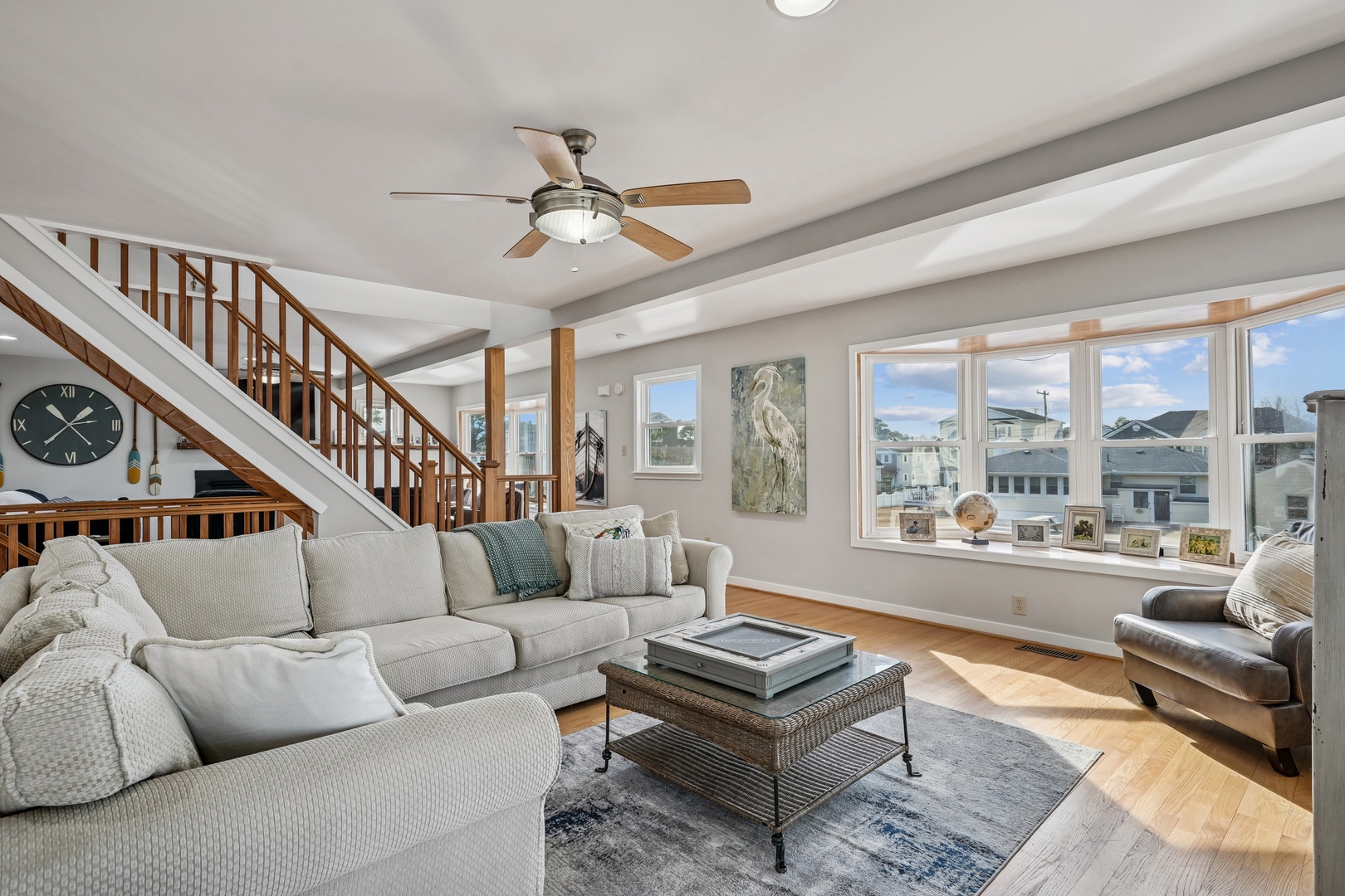 Relax in your bright, airy living room with plush seating, exposed beams, and peaceful neighborhood views through oversized windows.