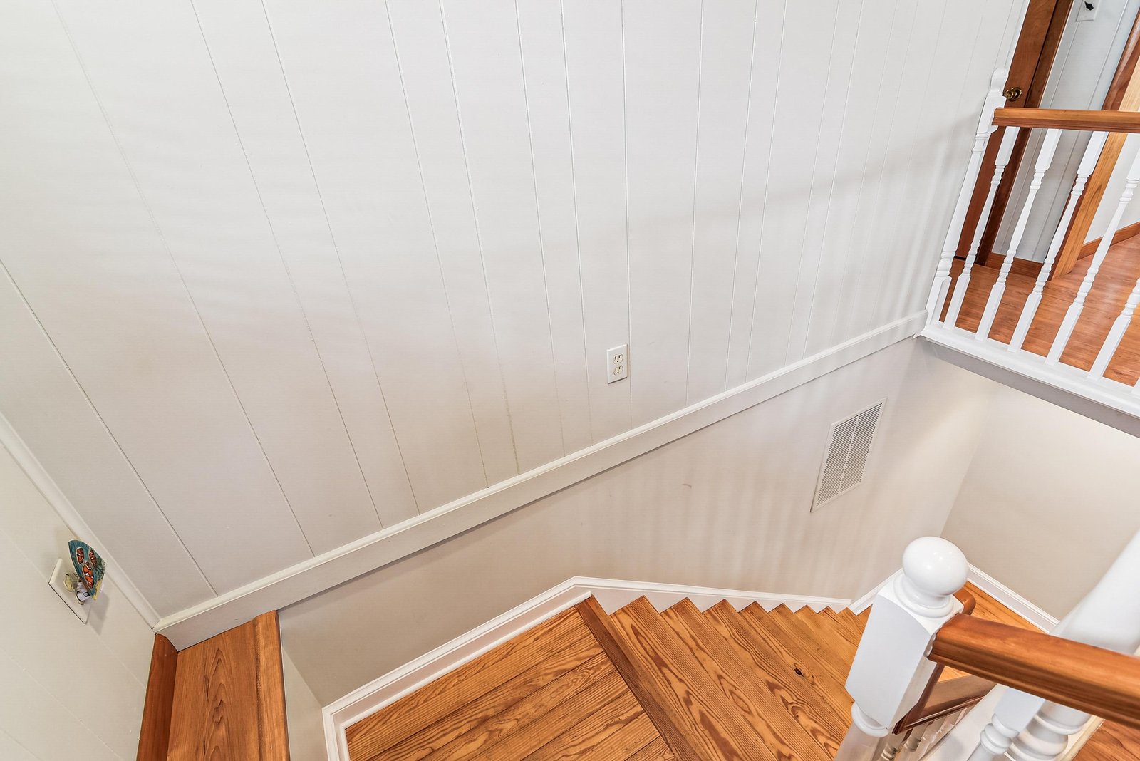 Gleaming hardwood stairs and shiplap walls create a warm, cottage-style entrance to your space.