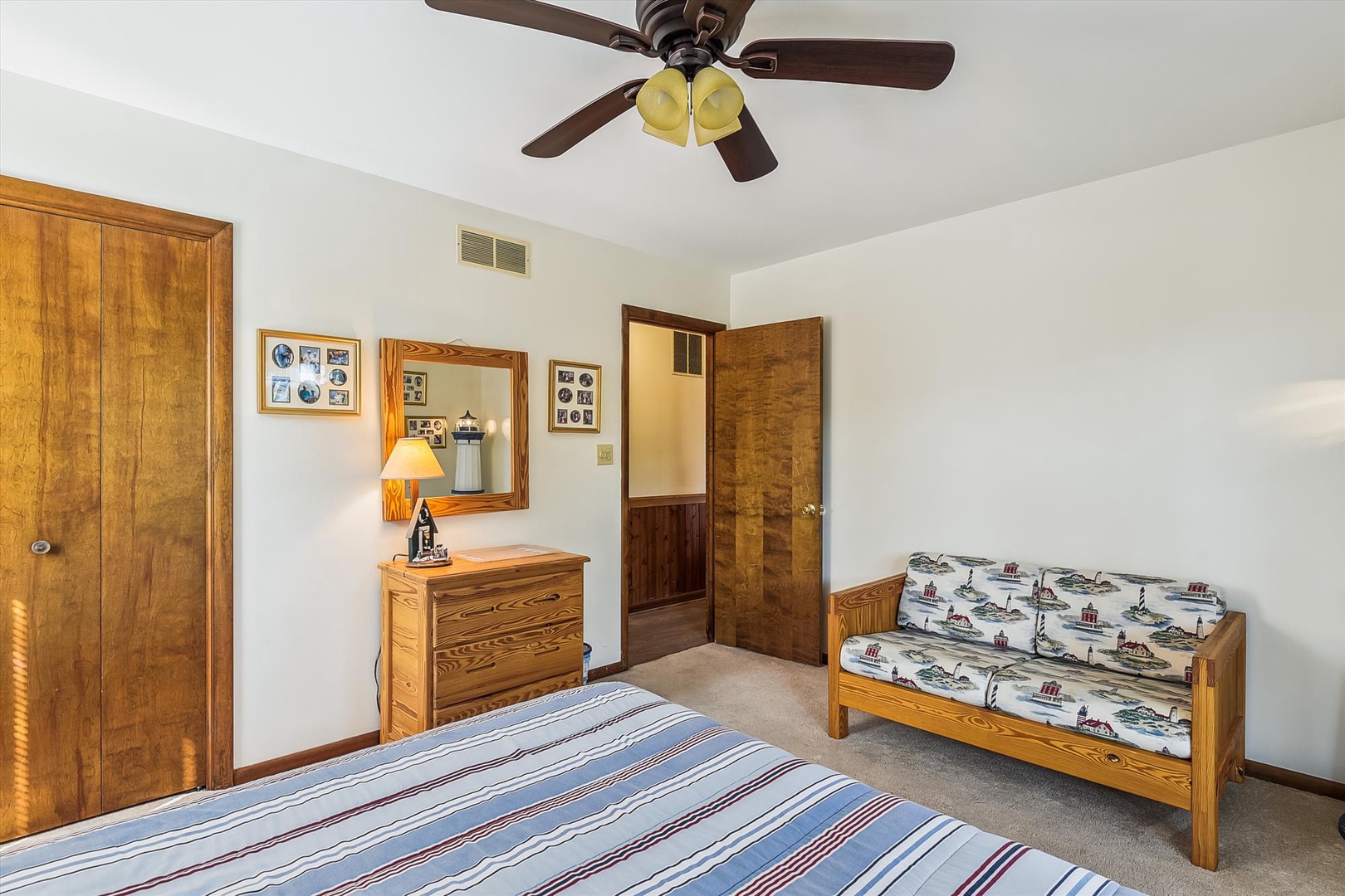 Step into your cozy bedroom featuring warm wood tones, a ceiling fan to keep you comfortable, and a charming bench where you can unwind and enjoy the peaceful ambiance.