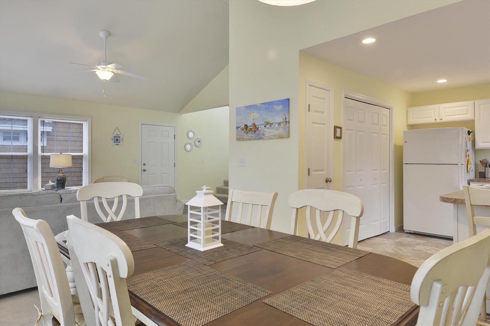 Your bright coastal retreat blends comfort and charm with soft hues, beach-themed art, and an open layout connecting the dining area, living room, and kitchen—perfect for relaxing meals and lazy evenings.