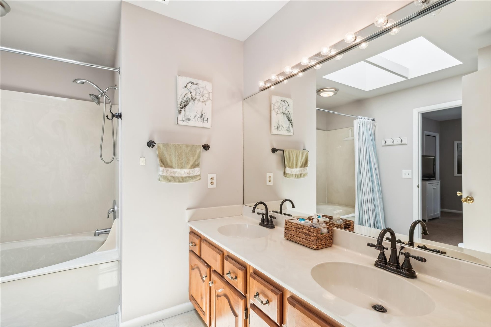 Refresh in your spacious bathroom featuring dual sinks, generous counter space, and bright natural lighting from the skylight above.
