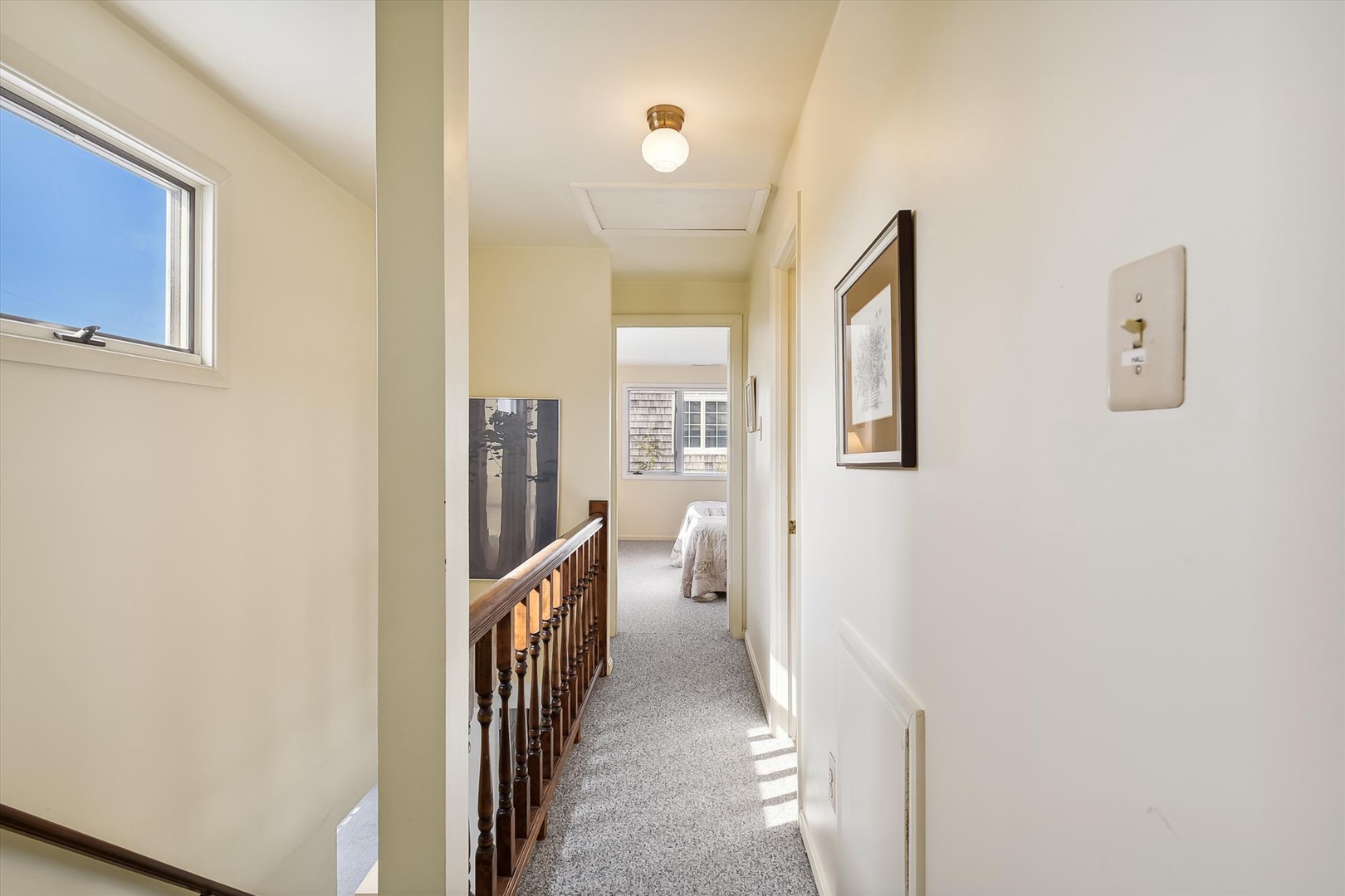 Natural light fills the upstairs hallway, where soft carpeting guides you to comfortable sleeping quarters. Thoughtful details like artwork and classic architectural elements add character to your home away from home.