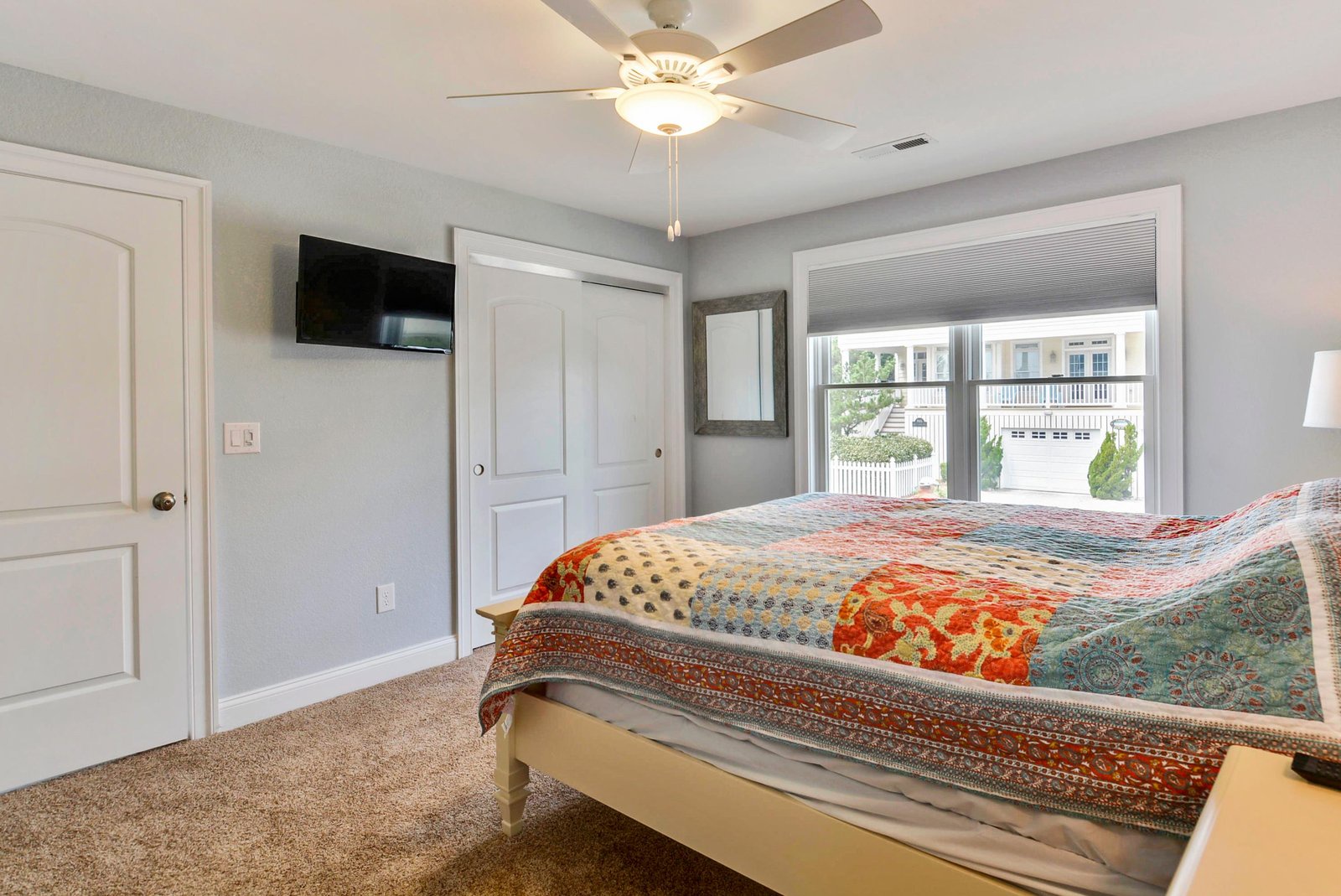 Settle into your cozy bedroom, where soft carpets meet breezy neighborhood views and a cheerful quilt invites you to rest after a day of exploring.