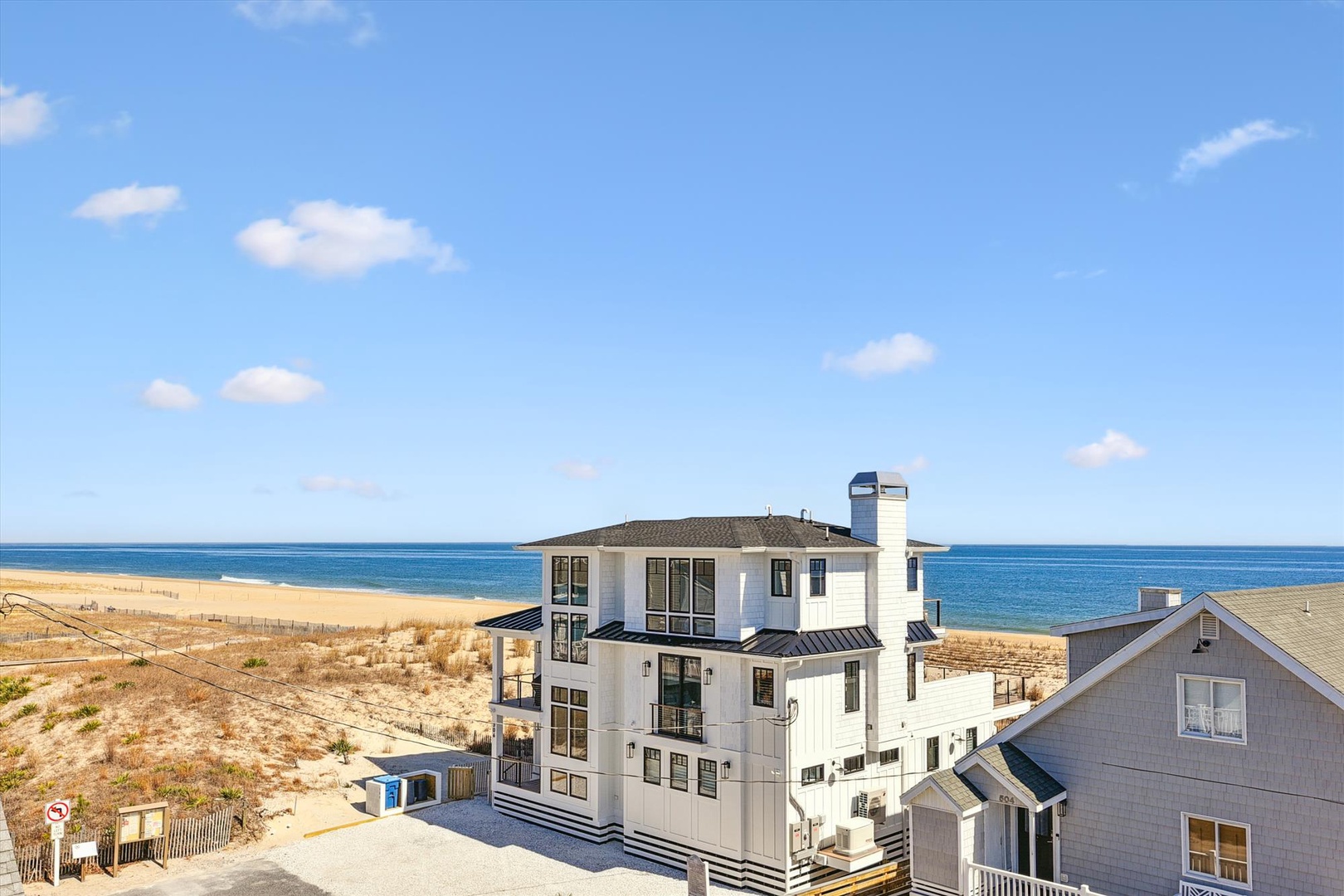 A beachfront property sits steps from golden sands and sparkling ocean waters, offering direct access to the shore and surrounded by a peaceful coastal neighborhood.