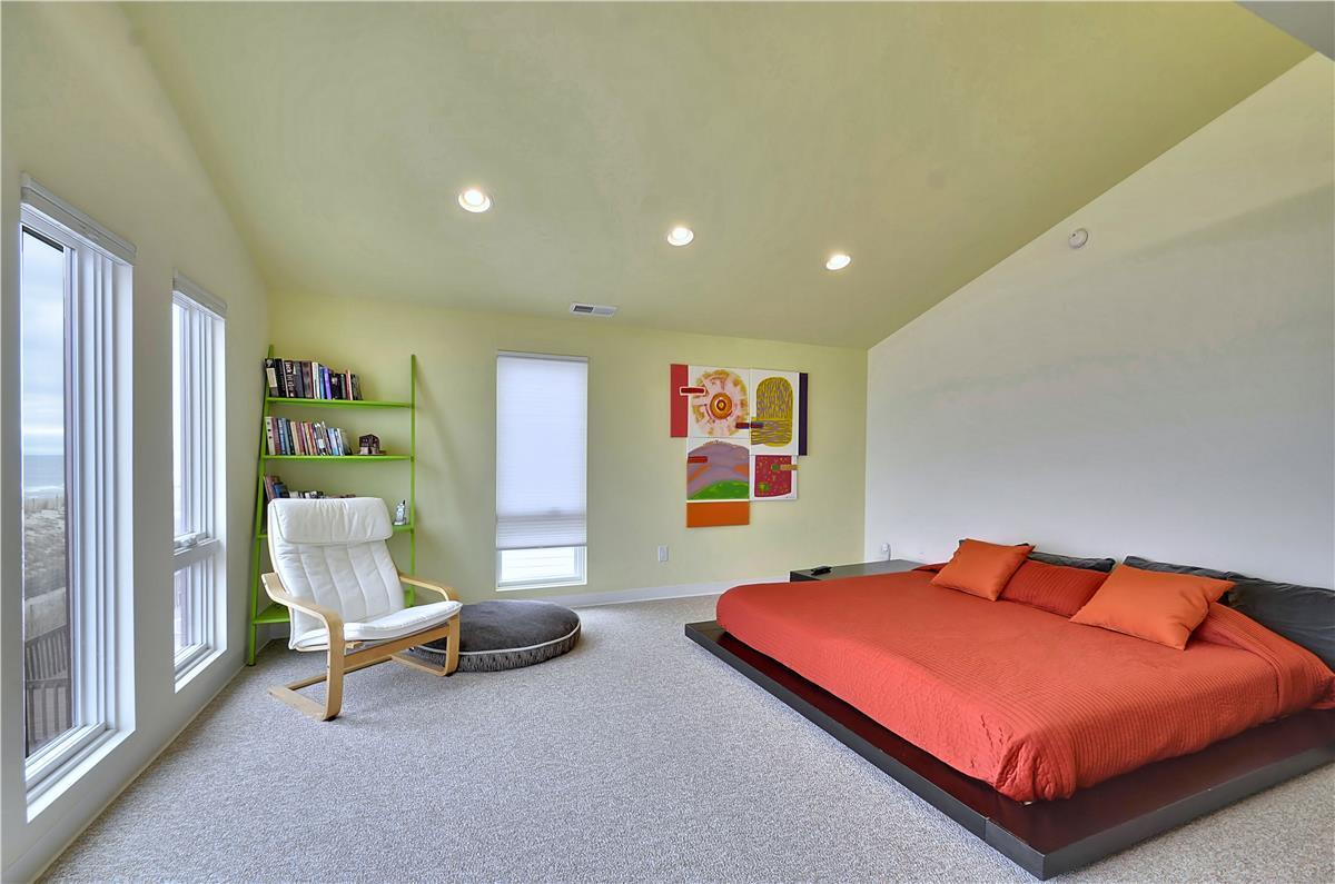 Your spacious bedroom offers a peaceful retreat with vibrant pops of color, plush carpeting, and a cozy reading nook by the windows where natural light fills the space.