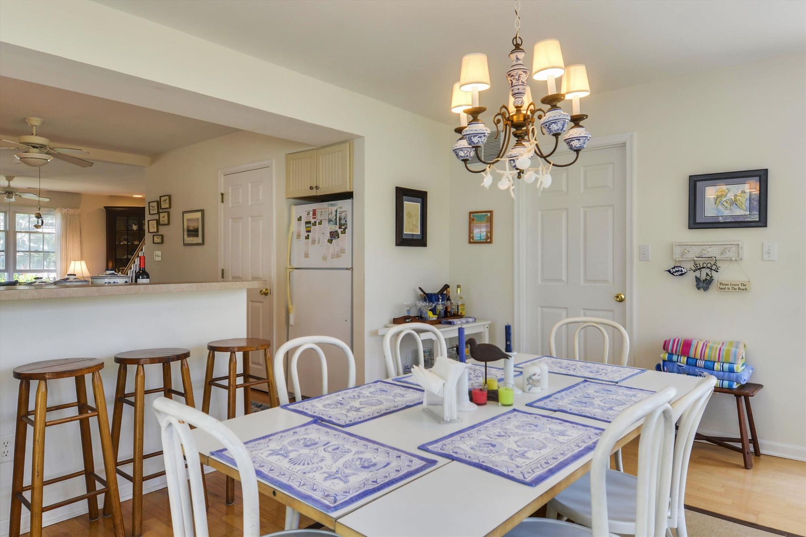 A charming dining space awaits your family gatherings, where elegant touches meet cozy comfort—from the decorative chandelier overhead to the cheerful blue-patterned placemats already set for your meal.