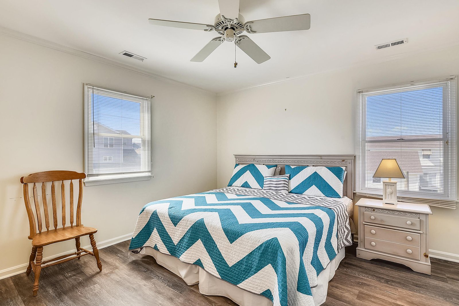Settle into your own bright bedroom, where crisp white walls and two sunny windows invite the day in. The ceiling fan keeps you cool, and that cheerful teal chevron bedding adds a playful touch of seaside charm.
