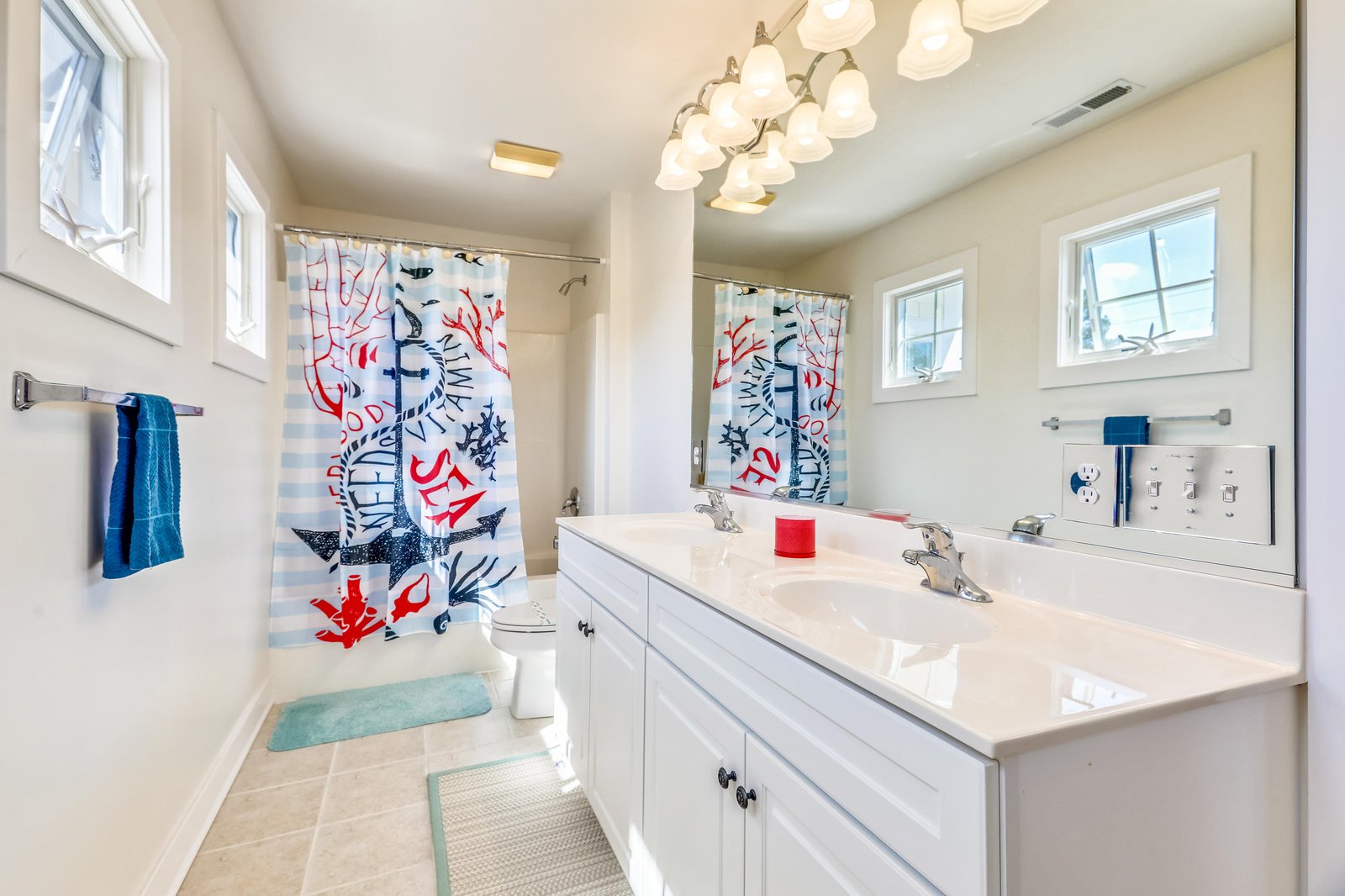 Refresh and unwind in your bright coastal bathroom with a playful nautical shower curtain and plenty of natural light streaming through.