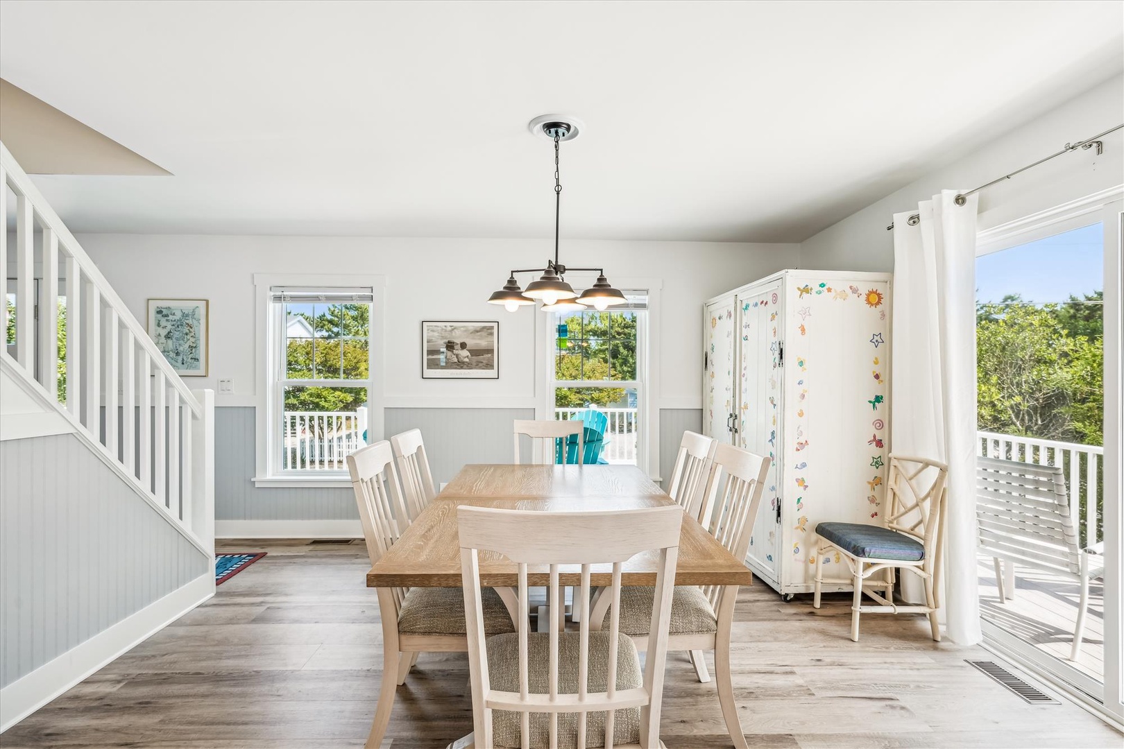 Gather around this inviting dining table, where natural light pours through windows framing lush greenery. Your meals here will feel bright and relaxed, with easy access to the outdoor deck.