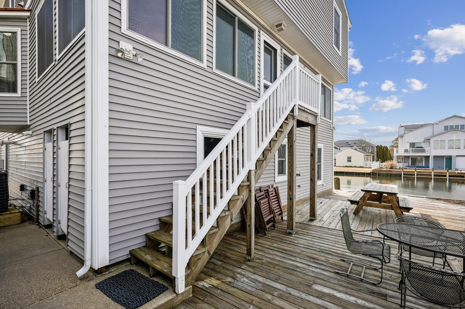 Waterfront deck with dining and lounging space opens to canal views, offering your perfect spot for morning coffee or sunset gatherings by the water.
