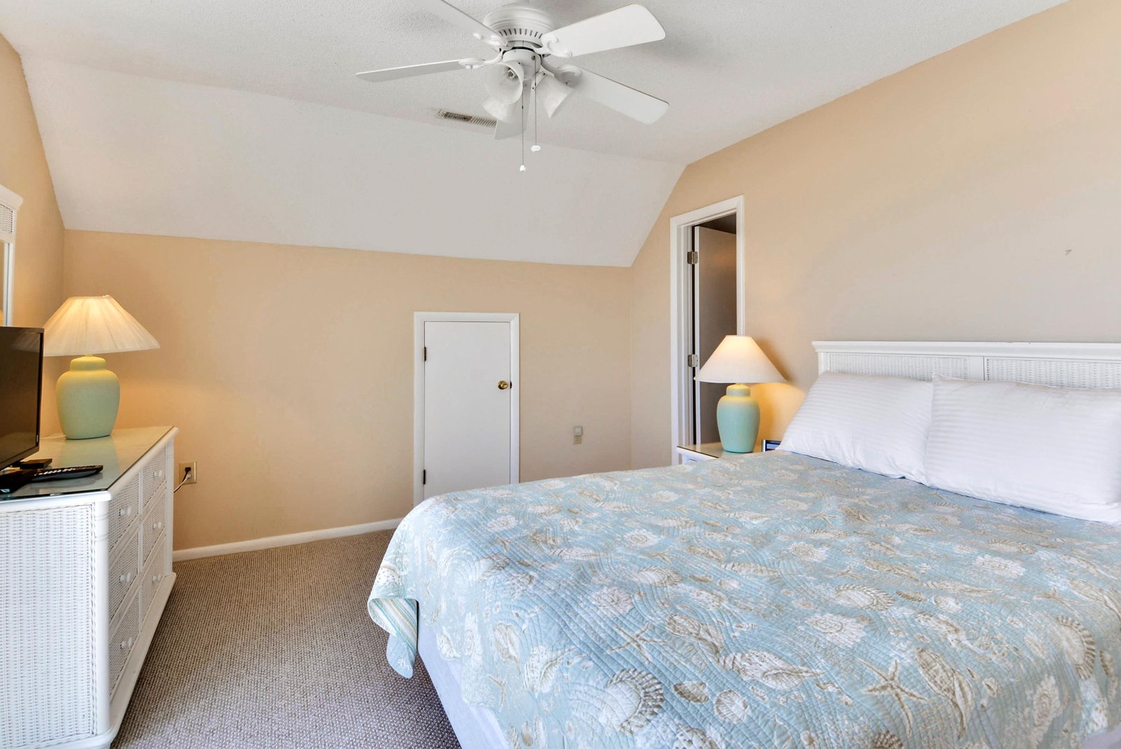 Settle into your peaceful retreat with soft coastal hues and vaulted ceilings. The gentle breeze from the ceiling fan and warm glow of bedside lamps create the perfect space to unwind after a day of adventure.