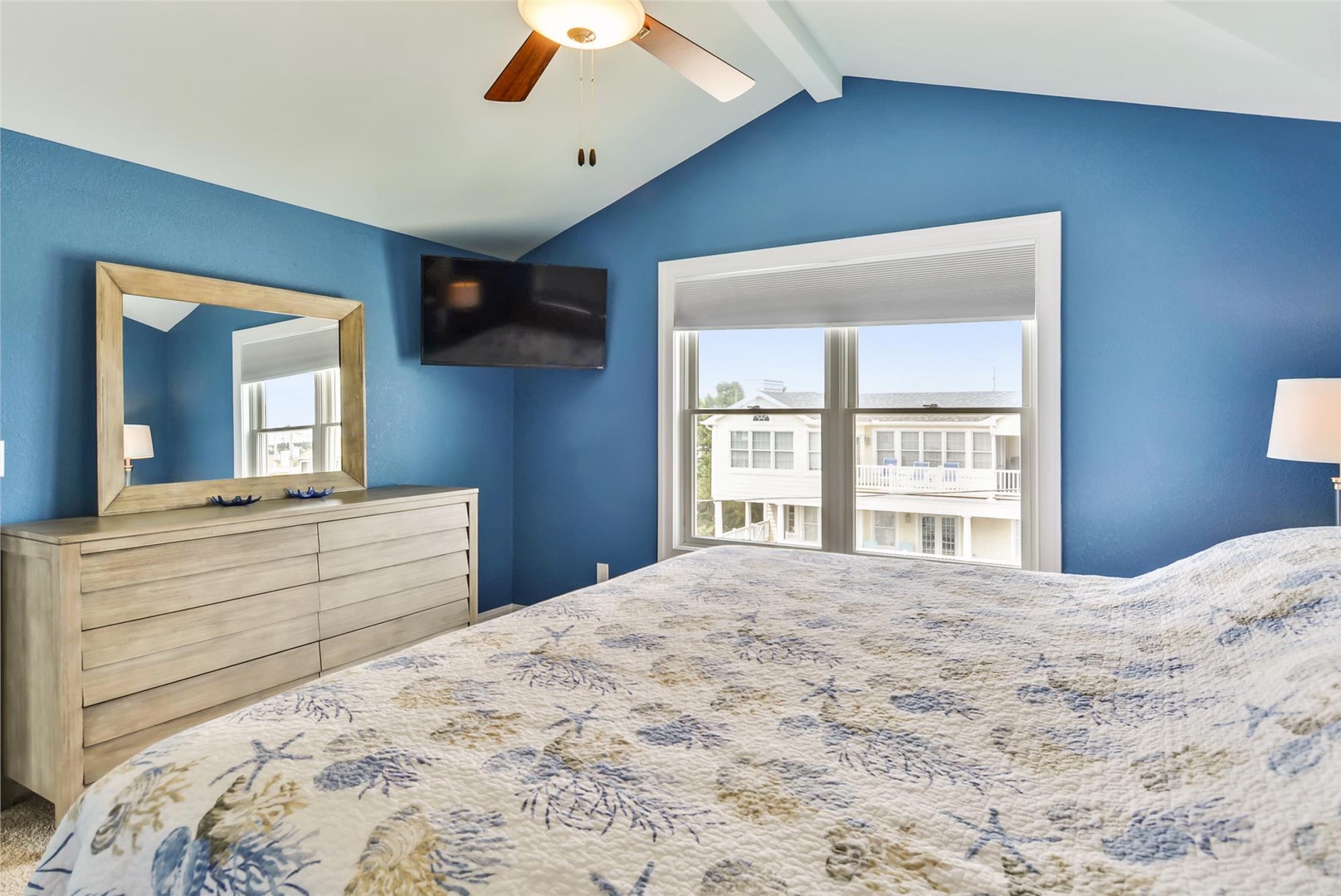 Unwind in your serene bedroom with soothing blue walls, comfortable bedding, and a ceiling fan to keep you cool. Wake to soft natural light streaming through your window.