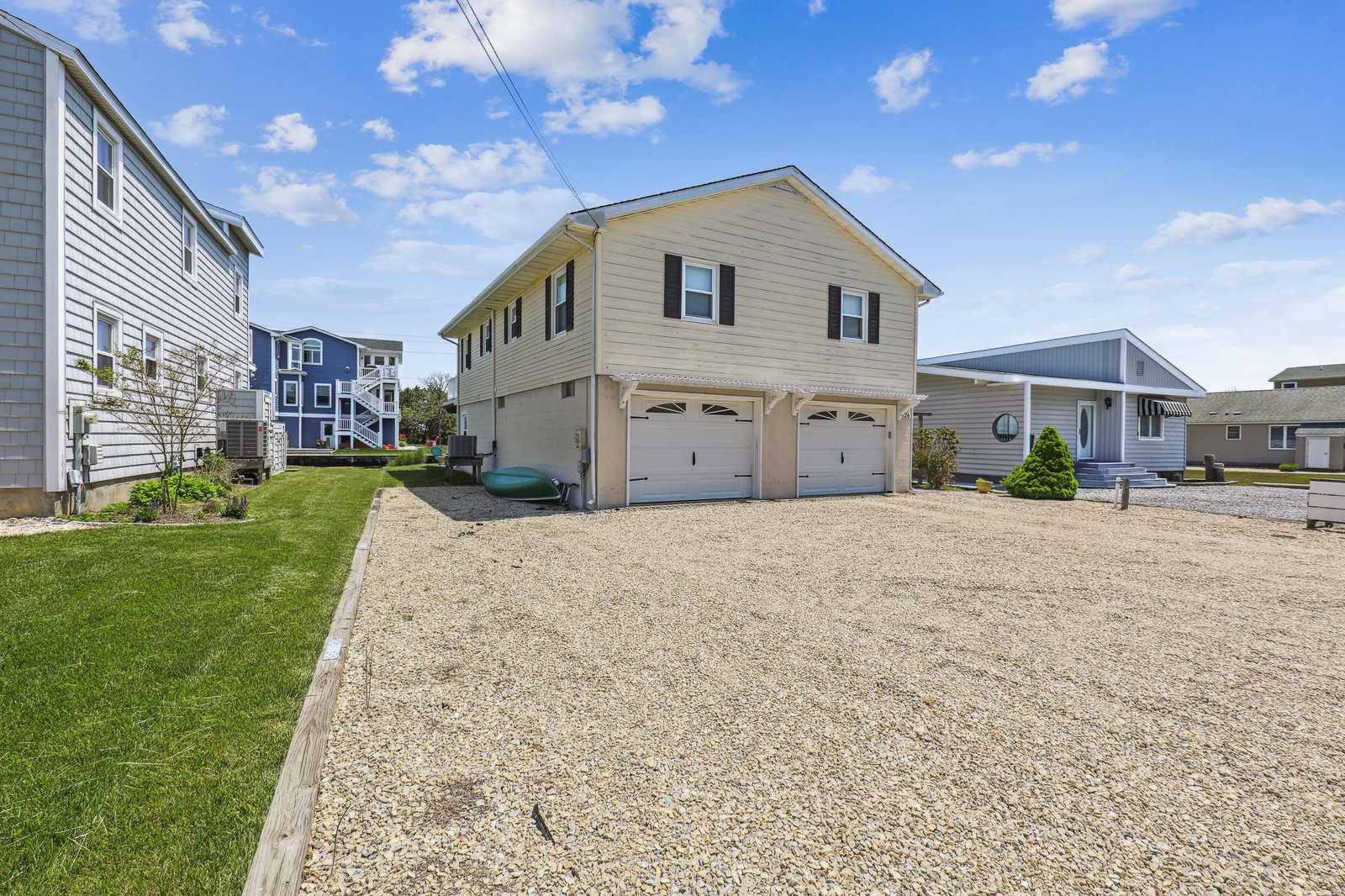The property sits in a peaceful coastal neighborhood with a spacious gravel driveway and two-car garage offering plenty of parking and storage for beach gear.