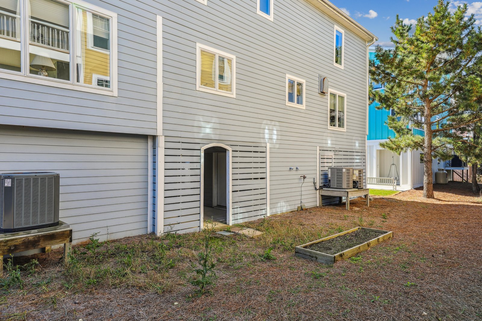 The property features fresh white siding, a climate-controlled ground level entrance, and a quiet backyard space under sunny skies.