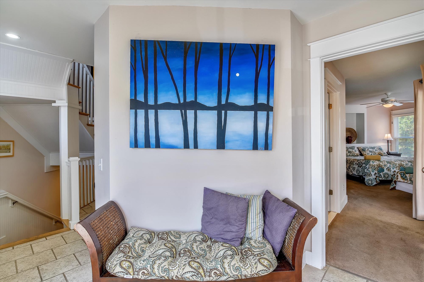 Settle into this cozy reading nook beneath tranquil artwork, where plush paisley cushions and rich wicker invite you to curl up with a book or simply unwind after exploring.