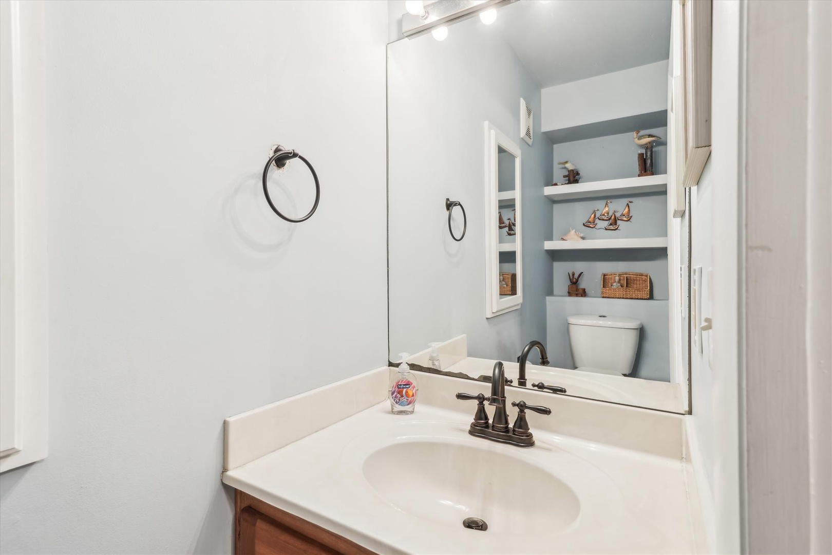 Freshen up in your bright, thoughtfully designed bathroom—featuring soft coastal tones, a vanity for your essentials, and charming built-in shelving that adds a homey, welcoming touch.