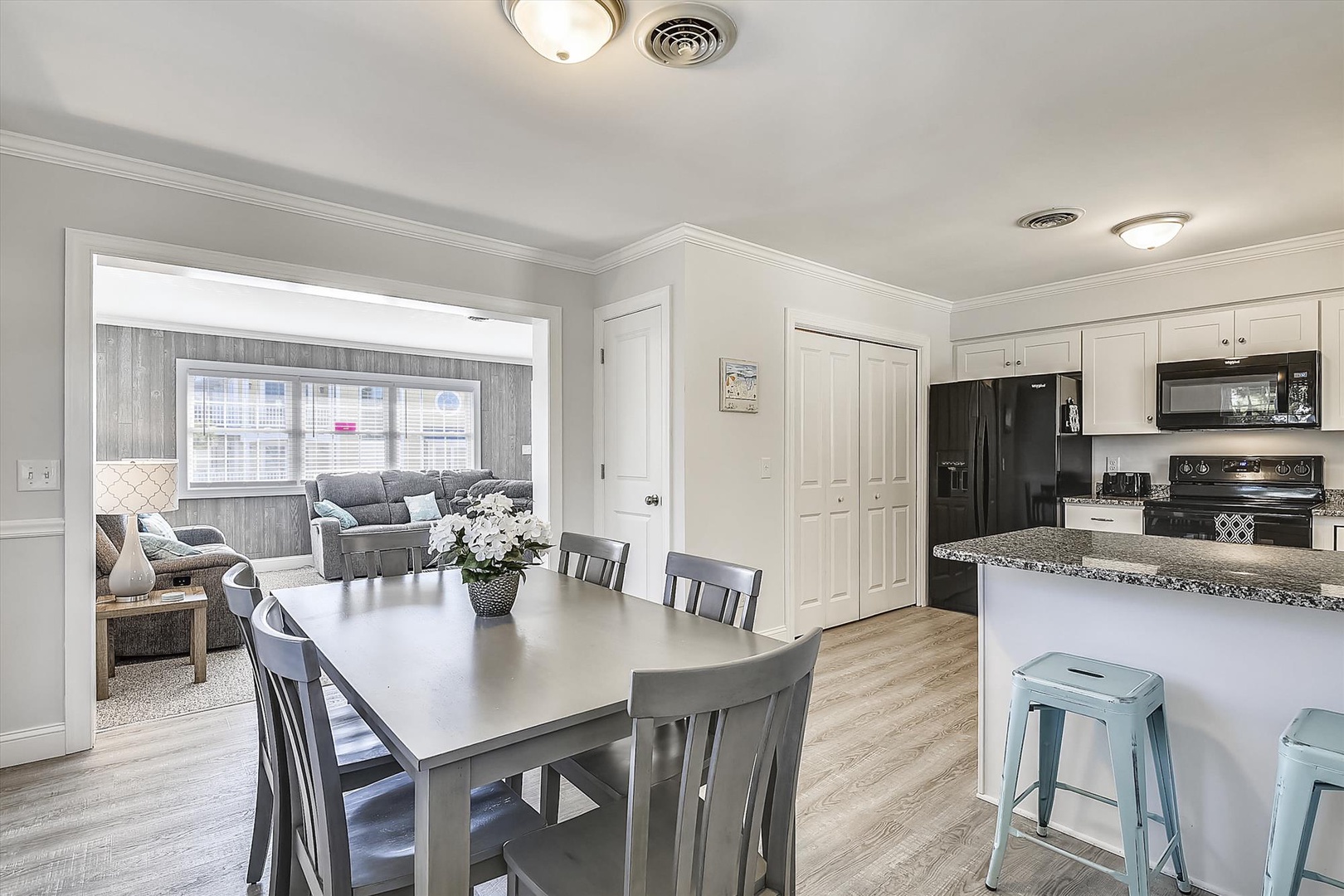 Gather with loved ones around the dining table, just steps from your fully-equipped kitchen where meal prep feels effortless. Relax in the inviting living area beyond, bathed in natural light.