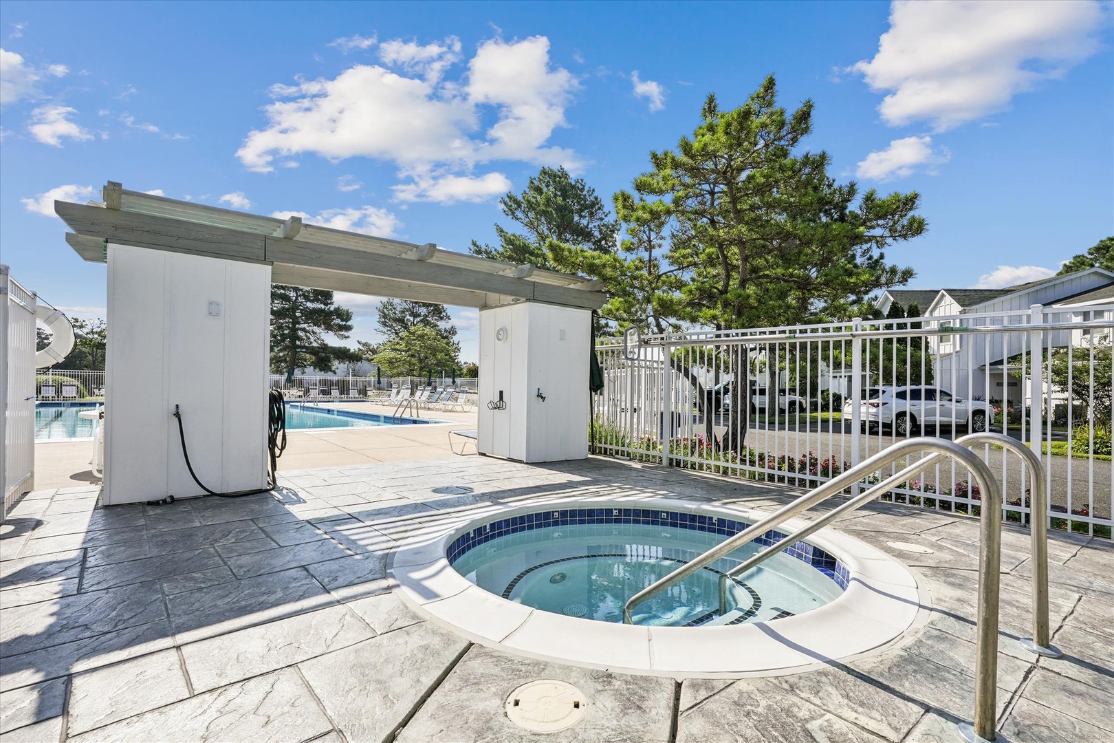Outdoor pool area featuring hot tub and swimming pool with modern facilities surrounded by mature landscaping.