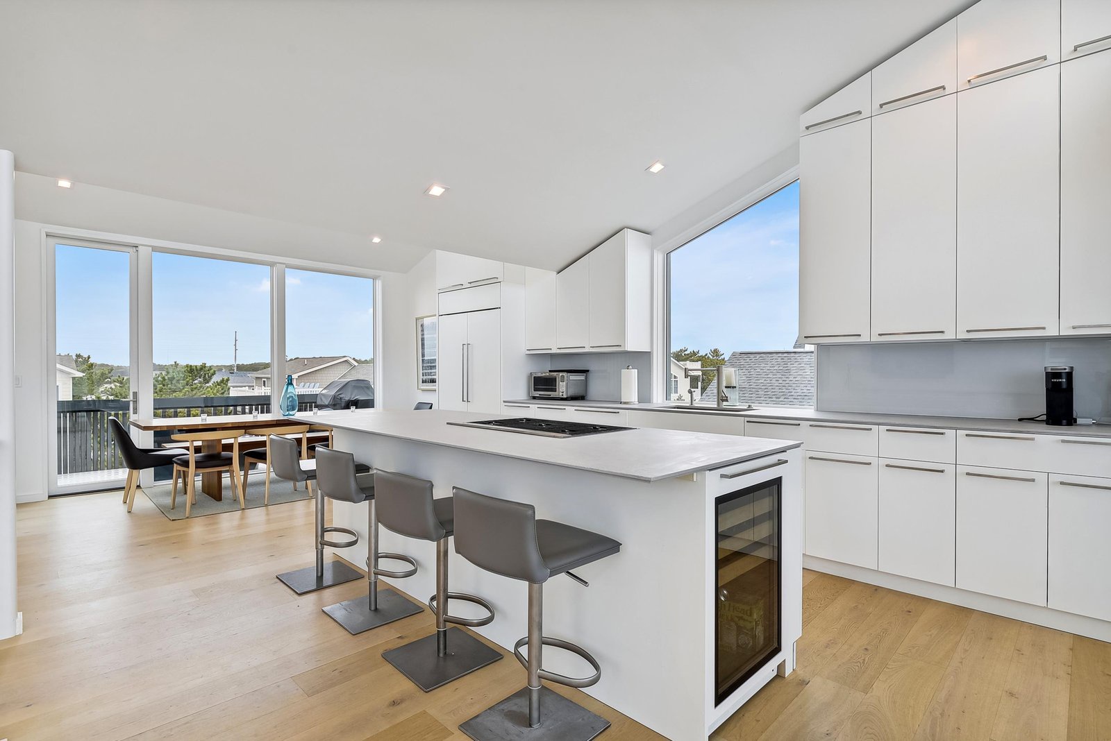 Your sleek, modern kitchen flows seamlessly into a sun-filled dining area, where floor-to-ceiling windows frame peaceful neighborhood views and fill your space with natural light.