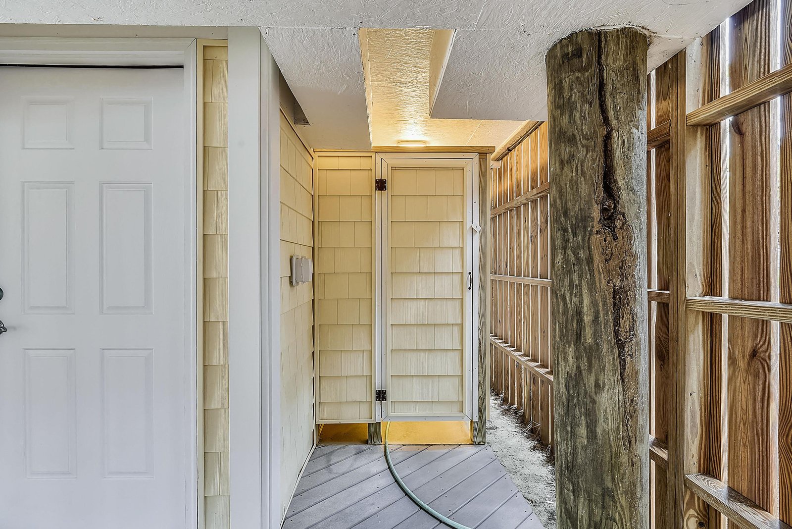 Your own private outdoor shower awaits, tucked behind wooden slats for a refreshing rinse after a day at the beach.
