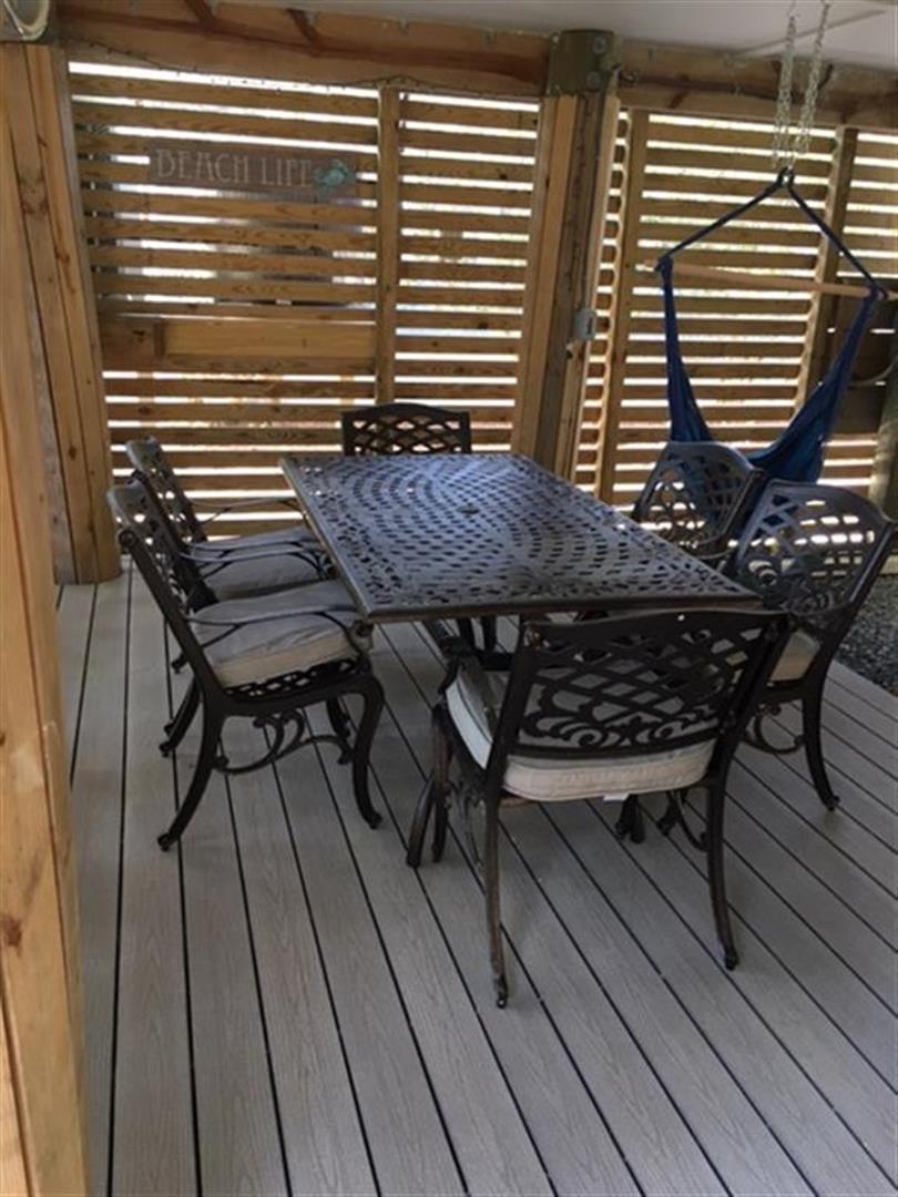 Your private deck features comfortable outdoor dining with decorative lattice privacy screens that filter gentle sunlight across the space.