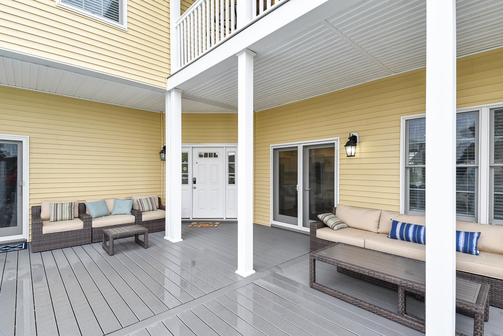 The property features a covered outdoor deck with comfortable seating areas, providing a welcoming entryway and relaxed space to enjoy the coastal air.