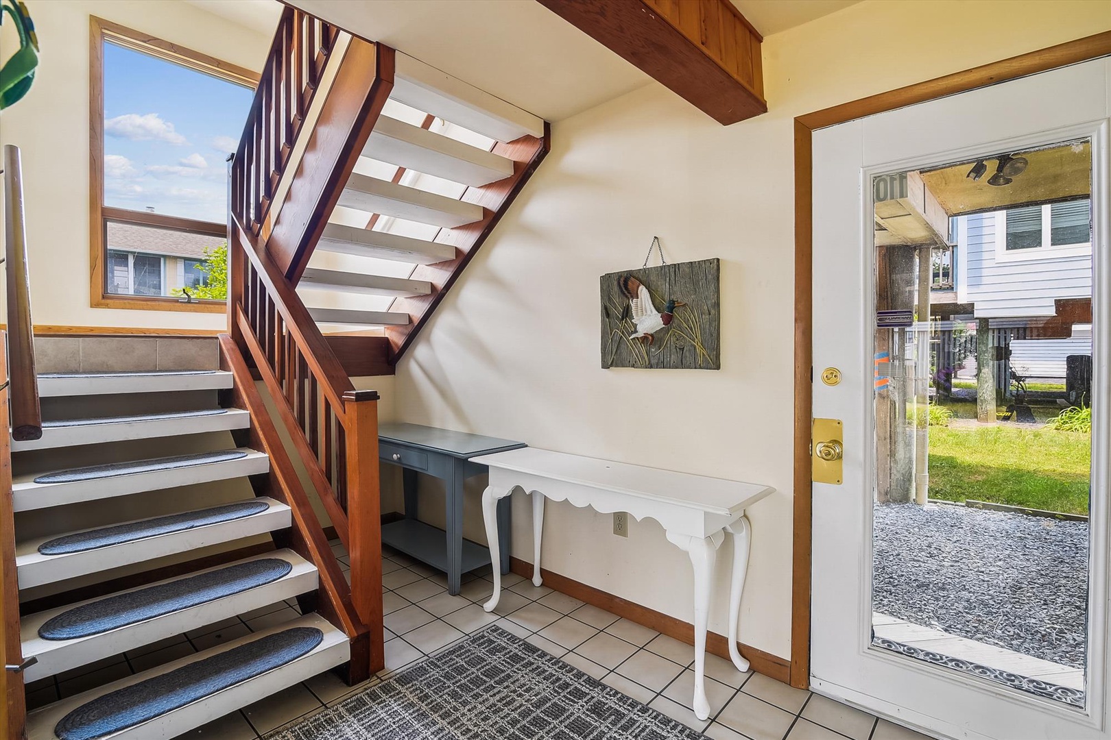 Step inside to a bright, airy entry with warm wood beams overhead and a charming staircase leading upstairs. Your vacation home welcomes you with a cozy, inviting feel.