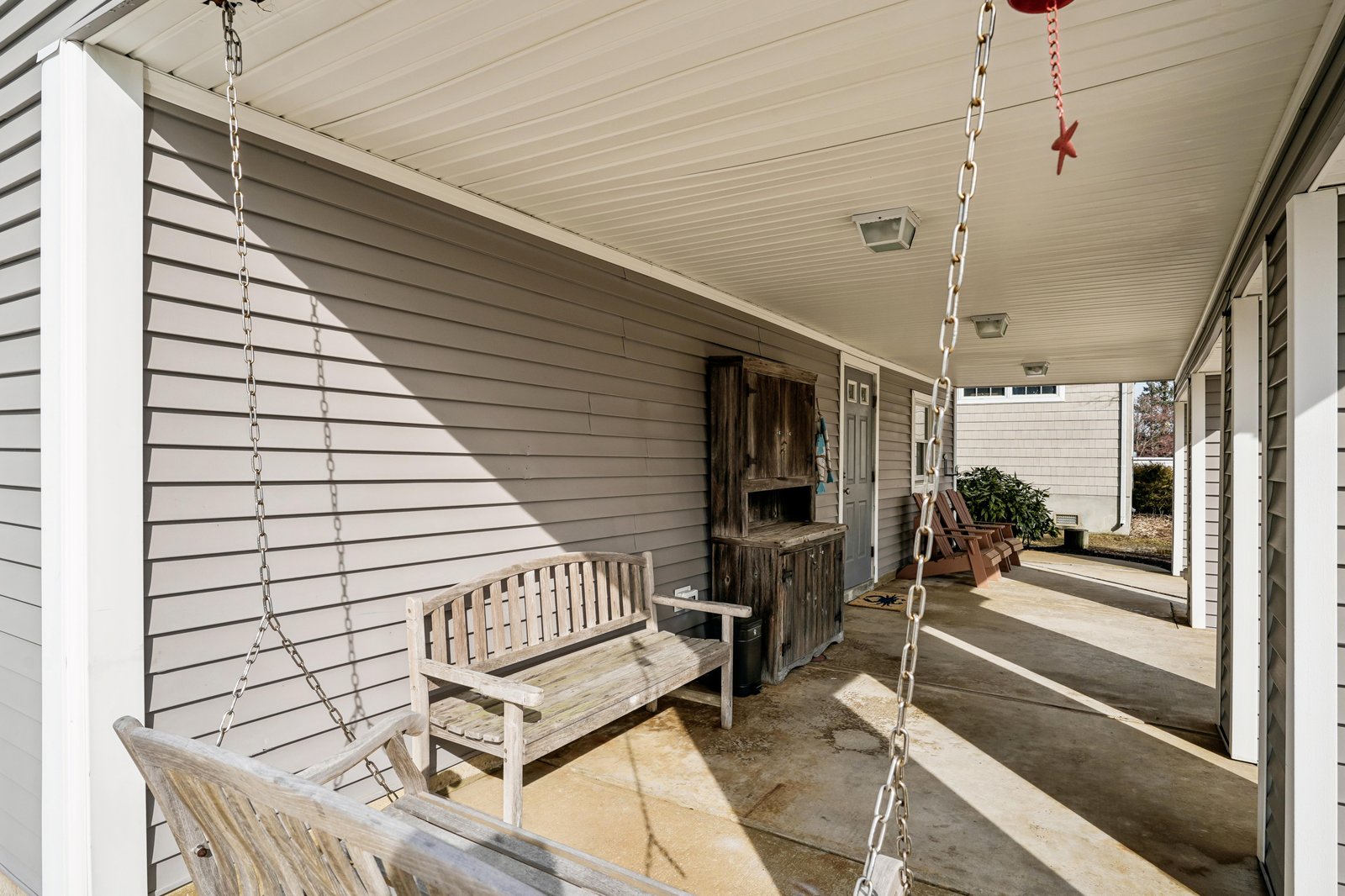 A covered porch welcomes guests with a charming wooden swing and rustic bench, offering a peaceful spot to relax before stepping inside your vacation retreat.