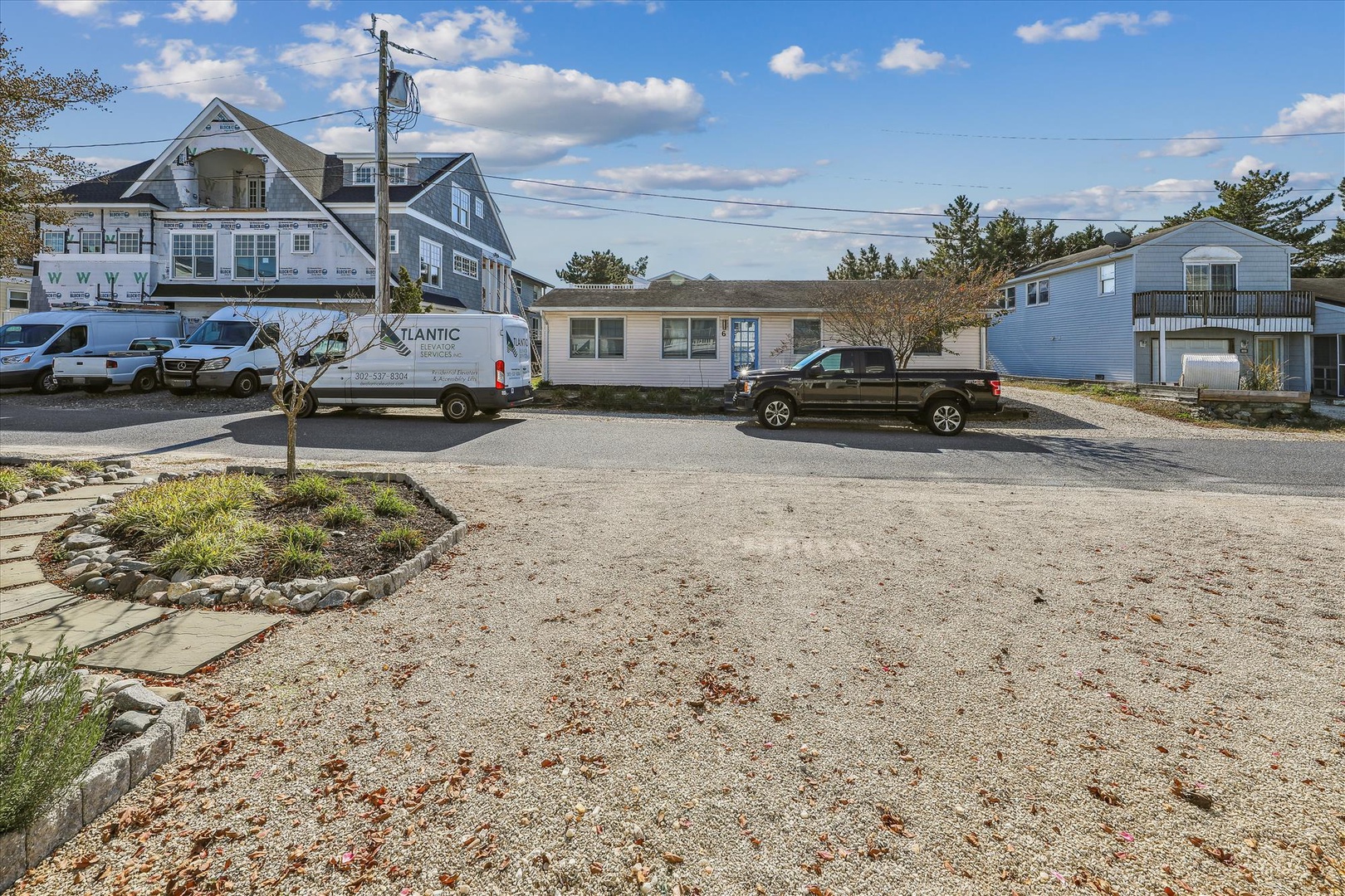 The property features convenient on-site parking with a spacious gravel lot accommodating multiple vehicles in a quiet residential beach neighborhood.