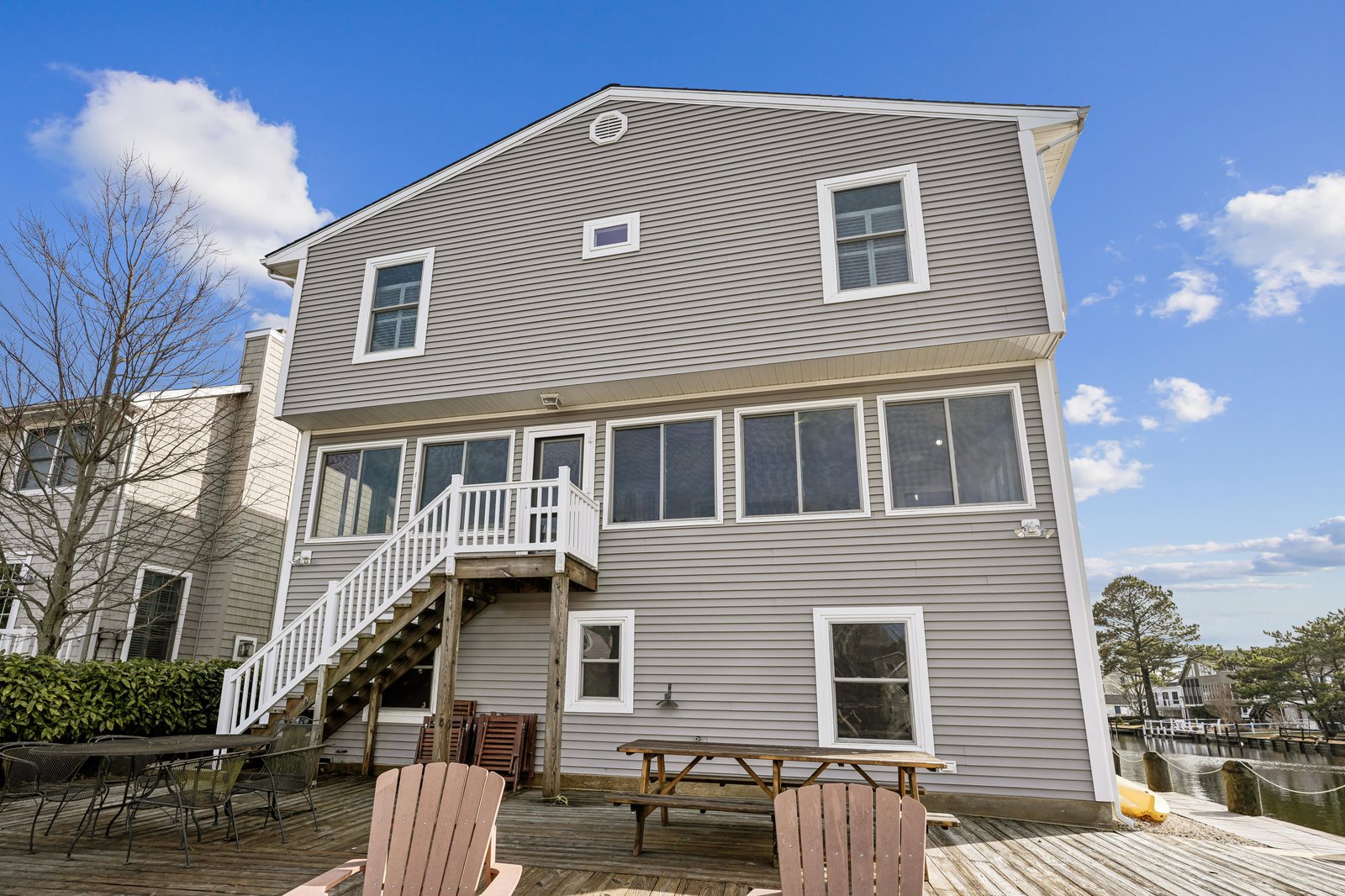 A three-story beachside rental featuring a spacious private deck with direct water access, perfect for outdoor dining and relaxing by the shore.