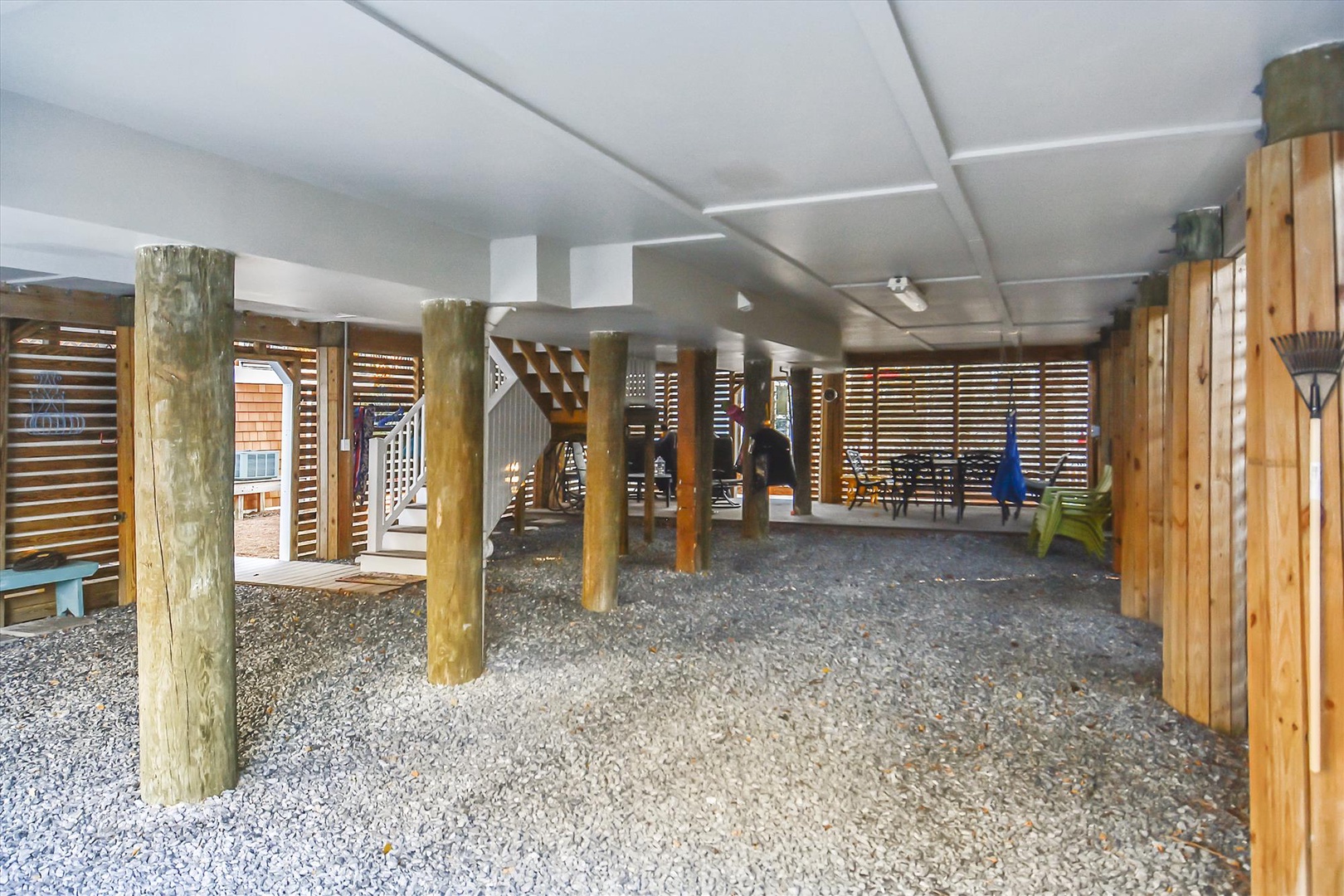 Covered outdoor space beneath the property with natural wood pillars and storage area, offering shelter and easy access to the grounds.