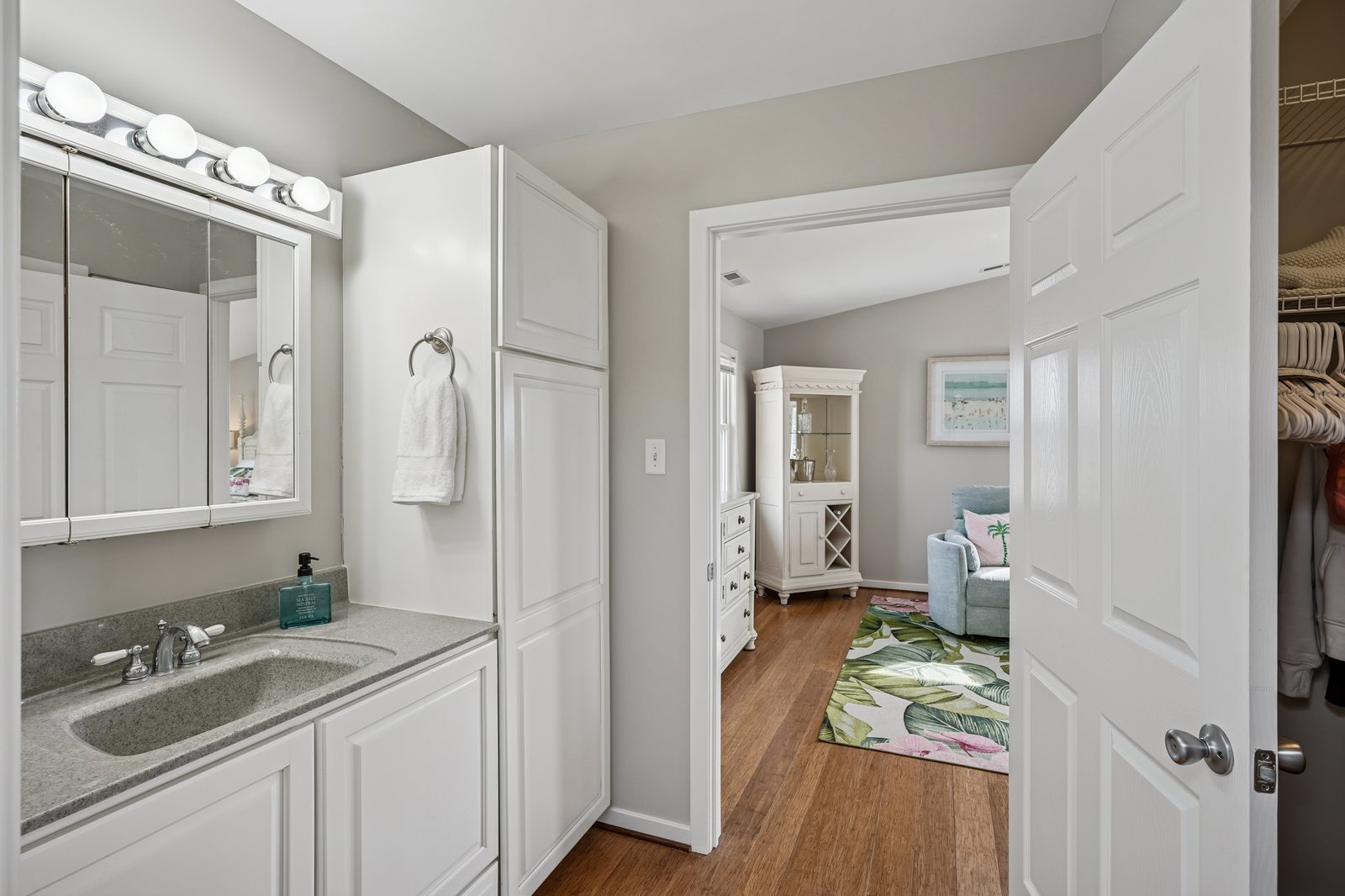 Step into your elegant ensuite bathroom with granite counters, white cabinetry, and Hollywood-style lighting for your perfect morning routine.
