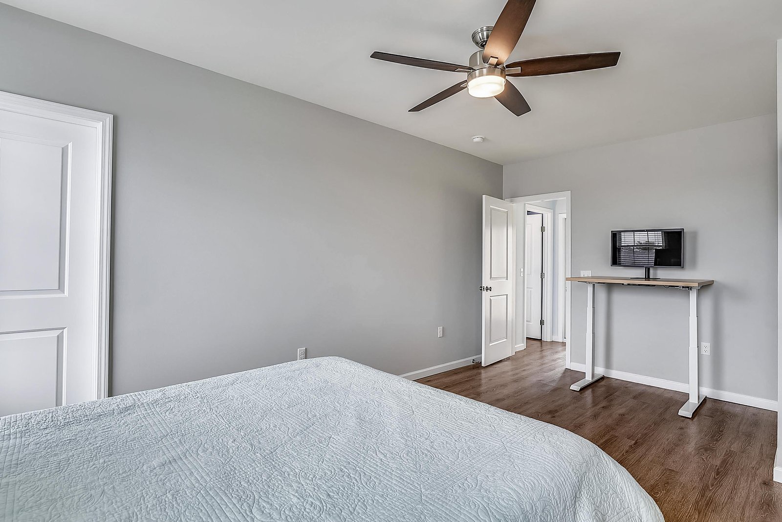 Unwind in your serene bedroom retreat, where soft gray walls and a gentle ceiling fan create a restful escape after a day of exploring.