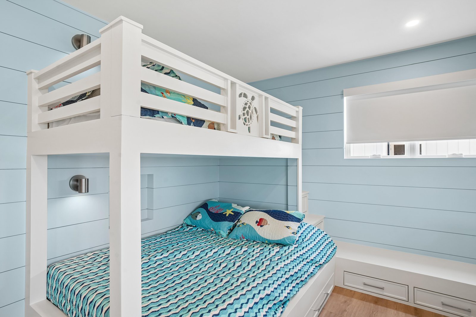 Coastal bunk beds with ocean-themed bedding make your beach getaway perfect for families—kids drift to sleep with sea turtles watching over them.