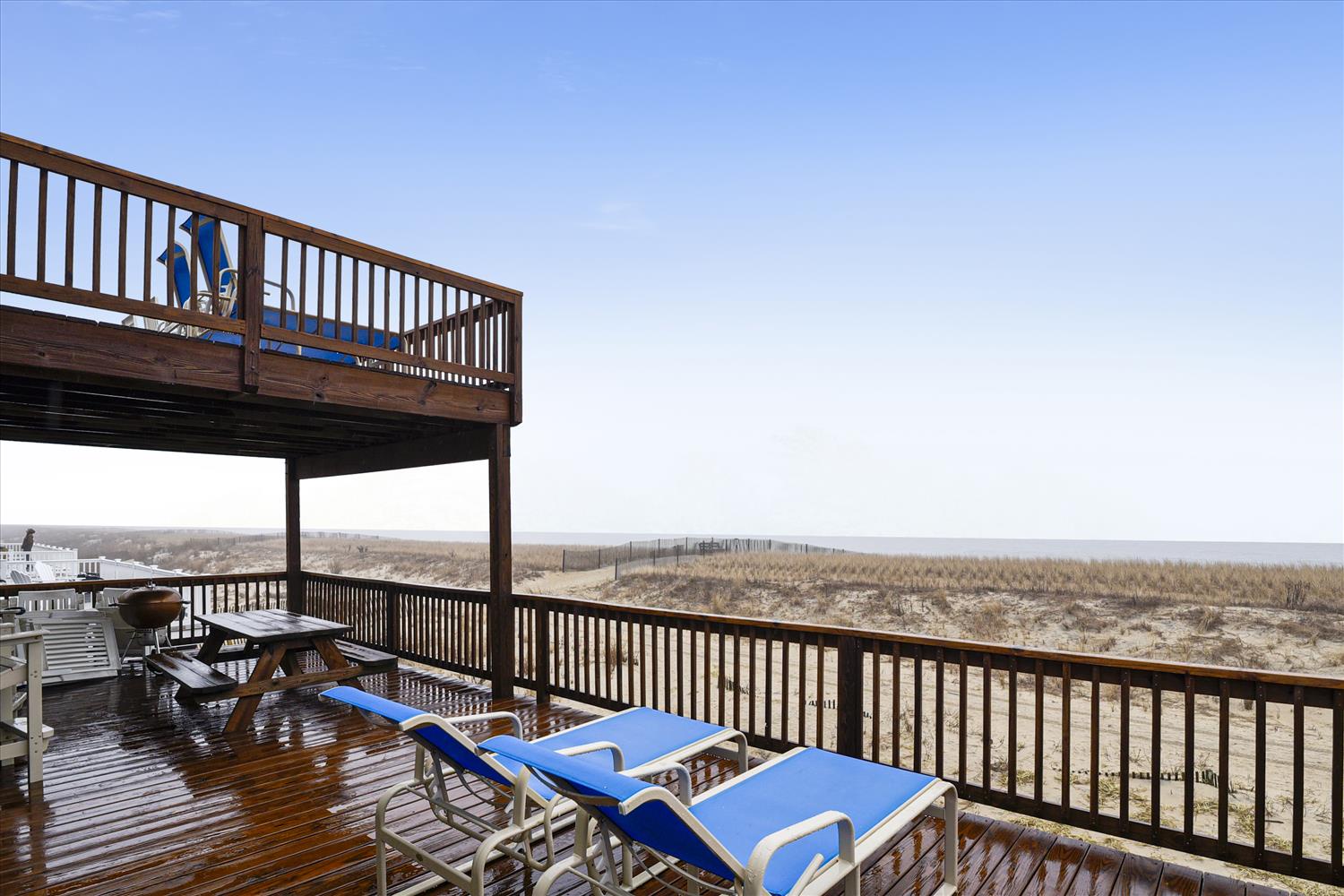 Multi-level deck offering breathtaking oceanfront views, complete with lounge chairs, a picnic table, and BBQ grill. Your perfect spot for coastal relaxation and outdoor dining.
