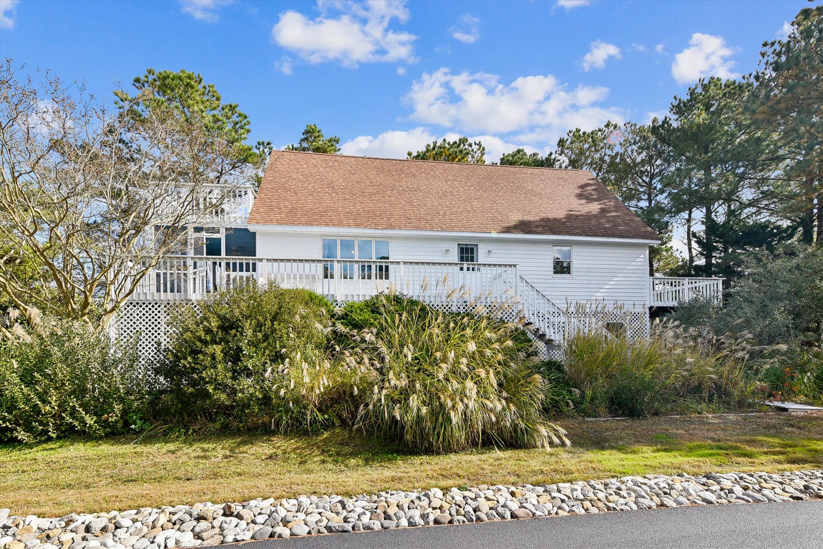 Charming coastal cottage with wraparound deck and mature landscaping creates a welcoming retreat for your vacation getaway.
