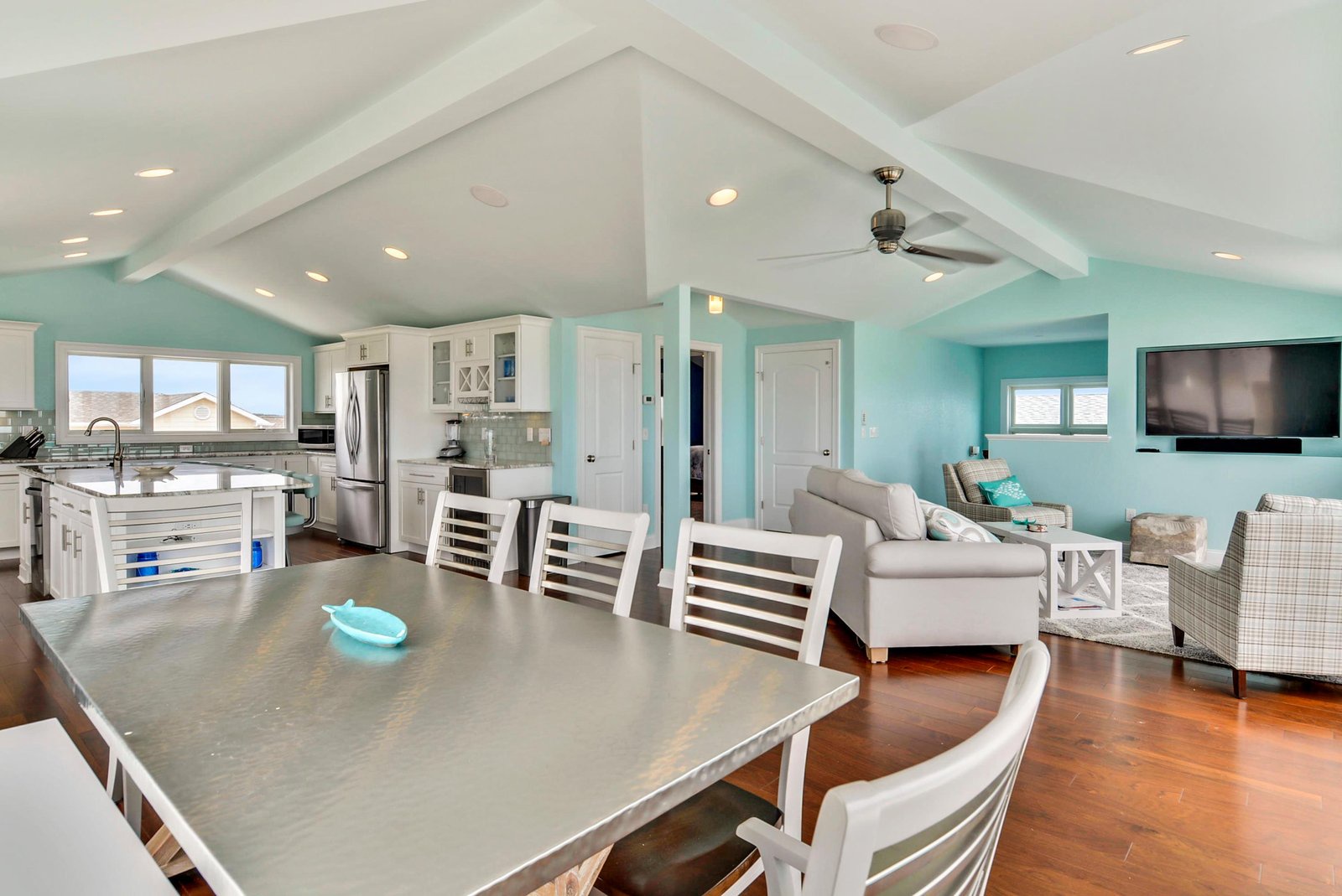 Step into this bright, coastal-inspired retreat where airy vaulted ceilings and soft turquoise walls create a tranquil escape. The open layout seamlessly blends kitchen, dining, and living spaces, perfect for gathering after a day of adventure.