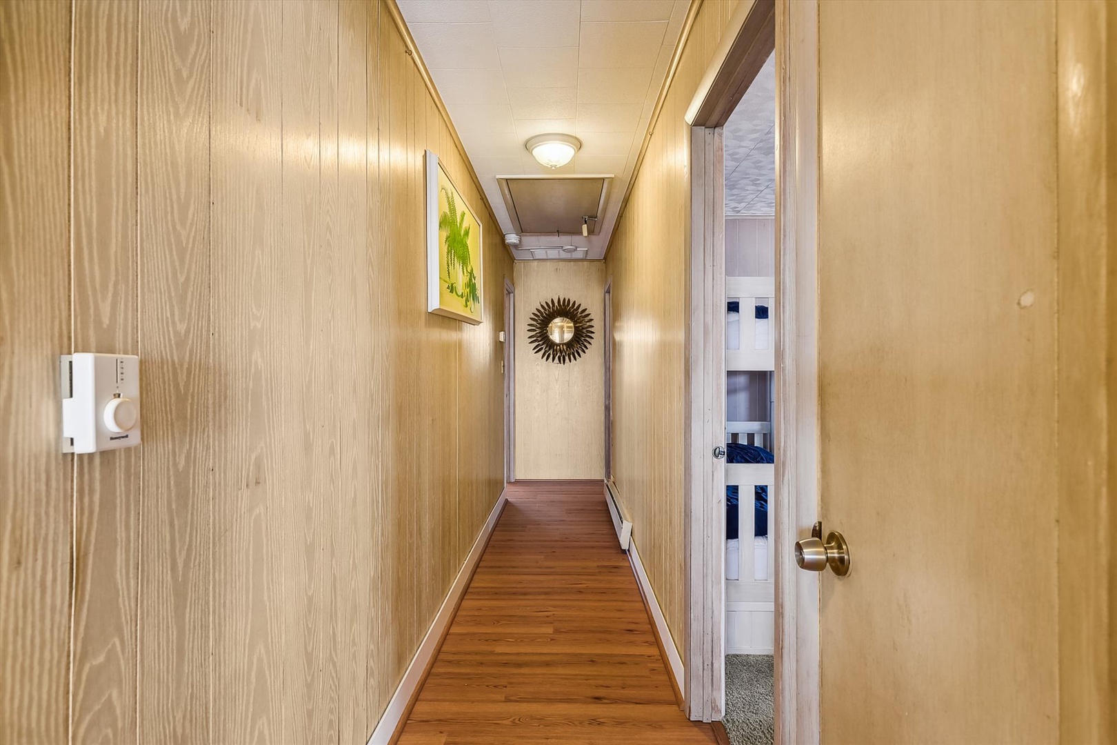 Warm wood-paneled hallway guides you to your private space, with soft lighting and simple decor creating a welcoming arrival to your retreat.