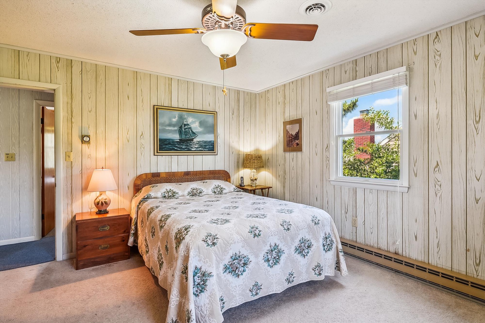 Unwind in your cozy bedroom with charming nautical touches, soft lighting, and a peaceful view of the lush surroundings through the window.