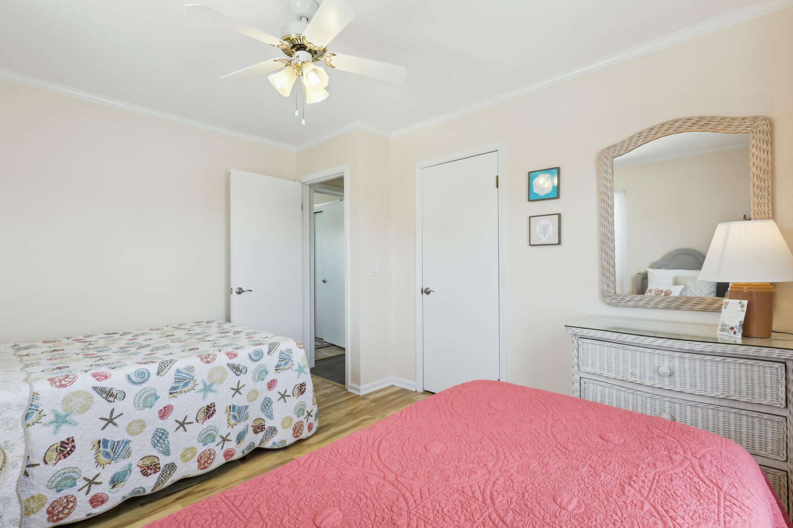 Your cheerful coastal bedroom features two comfortable beds dressed in beachy linens, a charming wicker dresser and mirror, and a ceiling fan to keep you cool during warm afternoons.