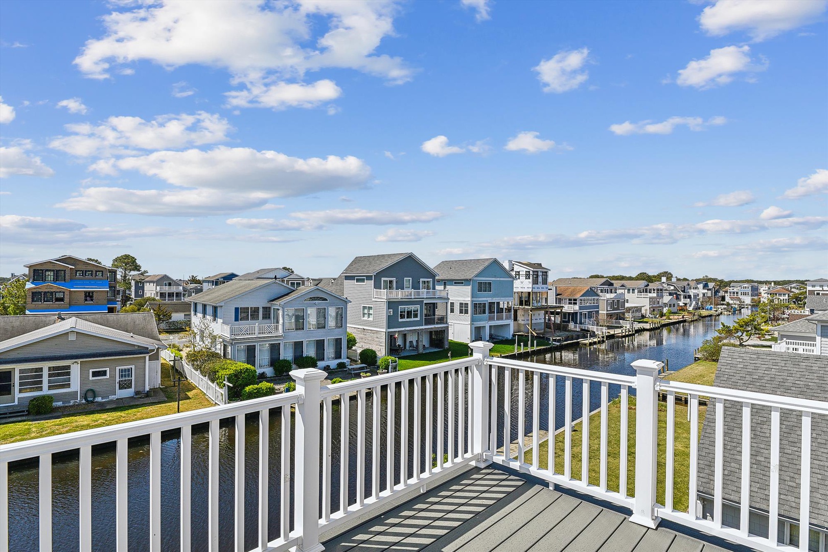 Sunny balcony overlooking a peaceful residential waterway and neighboring homes, perfect for relaxing with morning coffee or enjoying the coastal breeze.