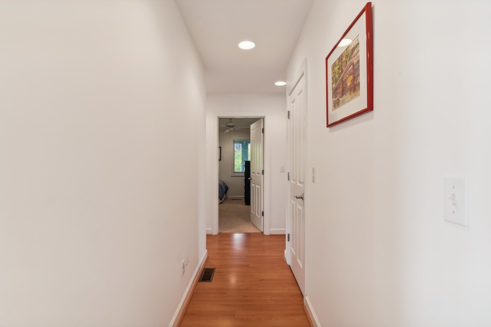 A bright, welcoming hallway leads you from room to room, with warm hardwood underfoot and crisp white walls that let natural light flow through the home.
