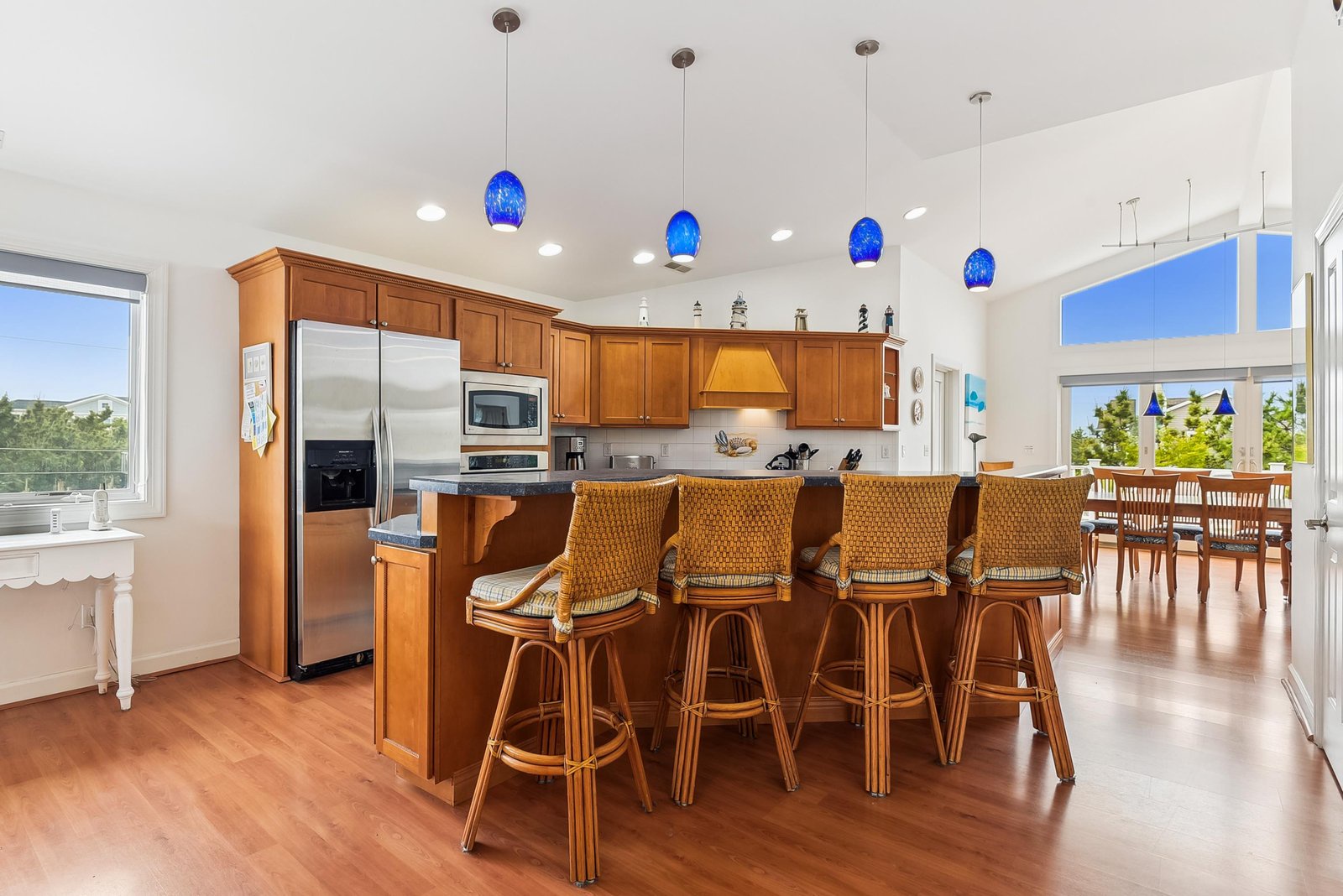 Gather around the spacious island in your gourmet kitchen, where vibrant blue pendant lights and warm wood finishes create an inviting space for cooking and conversation with loved ones.