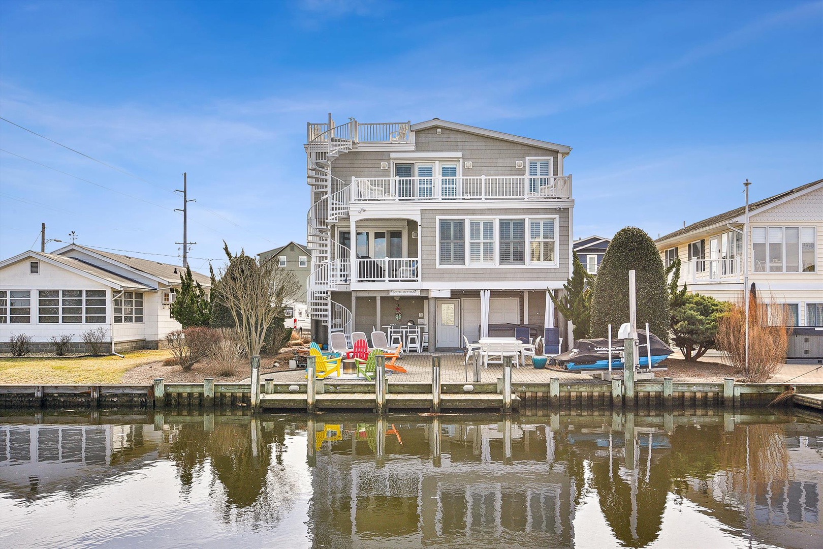 Waterfront vacation home with private dock and boat parking, featuring multiple decks and outdoor living spaces in a peaceful canal neighborhood.