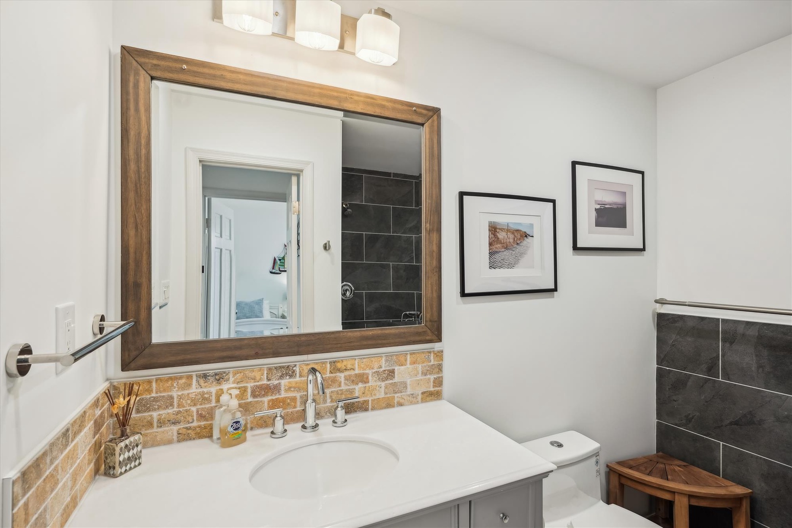 Step into your private sanctuary featuring a beautifully tiled shower, warm brick-style backsplash, and elegant wood-framed mirror—your cozy morning routine starts here.