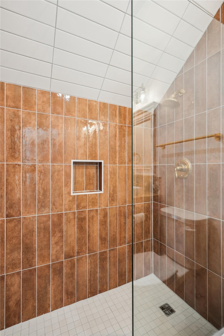 Step into your private walk-in shower, designed with warm terracotta and neutral tiles for a spa-like retreat after a day of exploring.