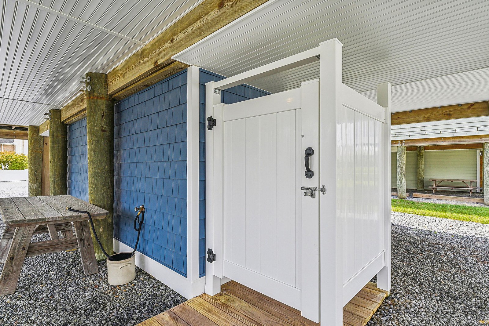 This property features a private outdoor shower stall, perfect for rinsing off after beach adventures or refreshing during warm days. The rustic beamed patio provides a shaded, inviting gathering spot.