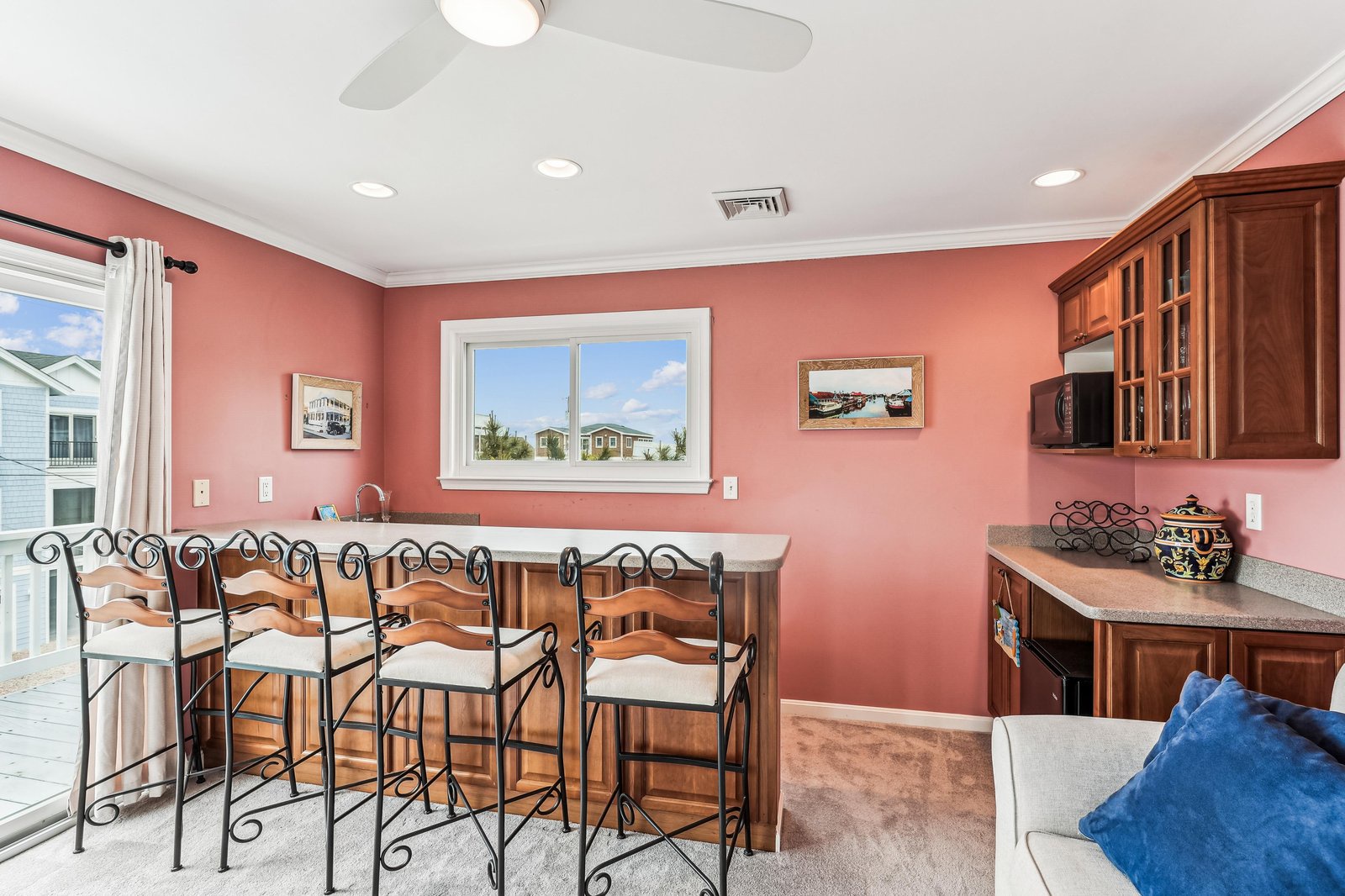 Gather around your private bar with friends and family, where rich wood cabinetry and cheerful coral walls set the tone for memorable evenings together.
